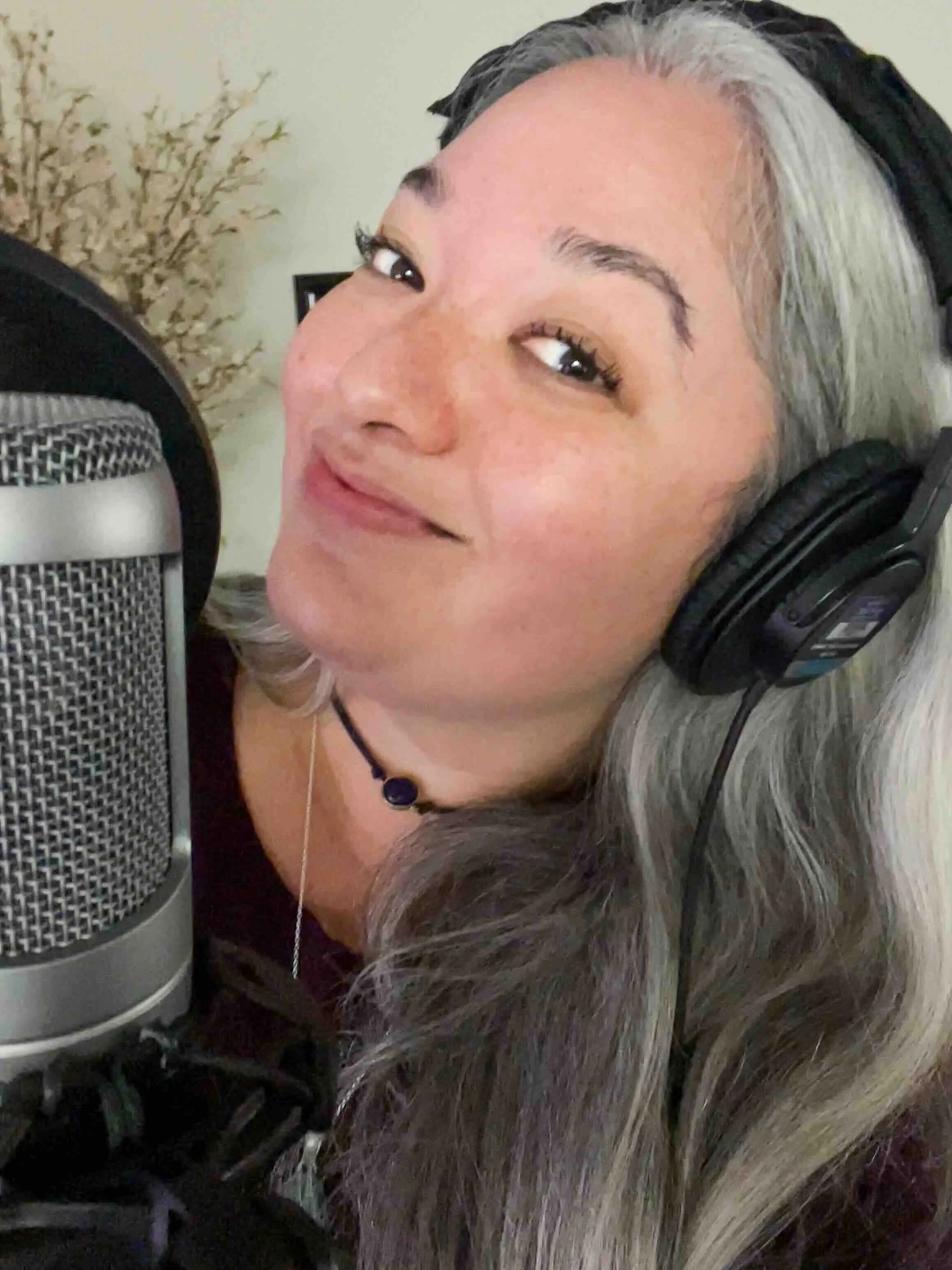 Hawaii voiceover actor, Cassie Favreau-Chung, in the studio with headphones and a microphone recording a commercial voiceover for a retainer client.