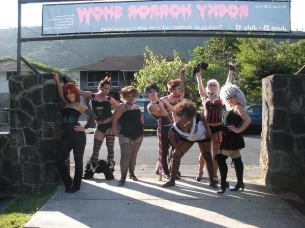 ROCKY HORROR SHOW AT Manoa Valley Theatre. Actress Cassie Favreau-Chung plays Magenta. Group of women in lingerie costumes posing under a sign that reads "Booty Workshop".