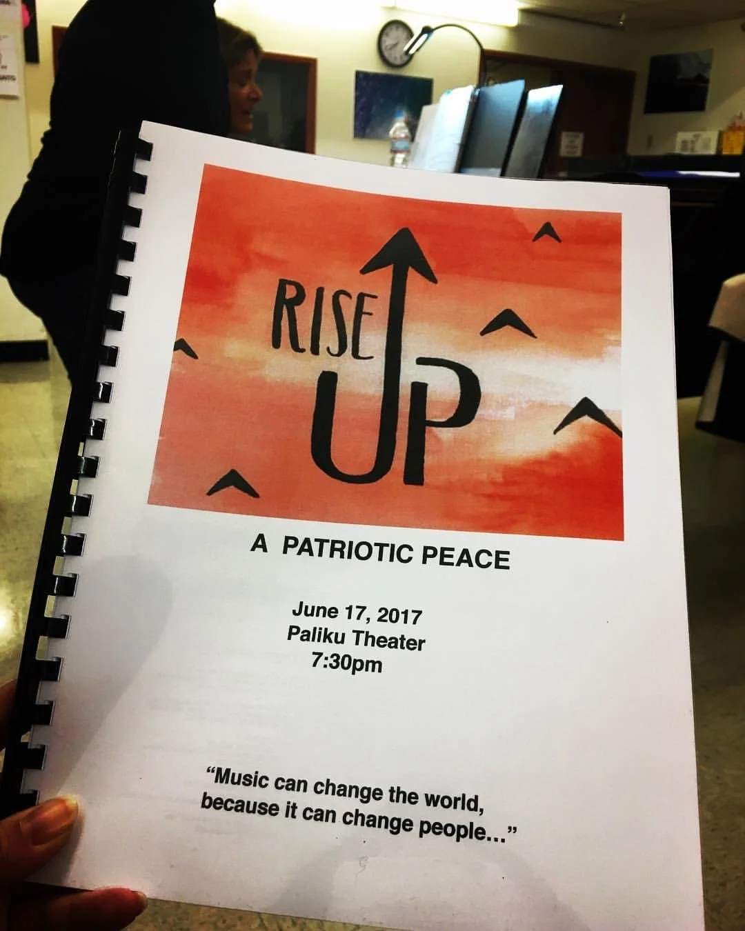 Flyer for an event called 'Rise Up' with a subtitle 'A Patriotic Peace.' The event took place on June 17, 2017, at Paliku Theater at 7:30 pm. The flyer has a background with a red and orange watercolor style and features black birds flying. There is 