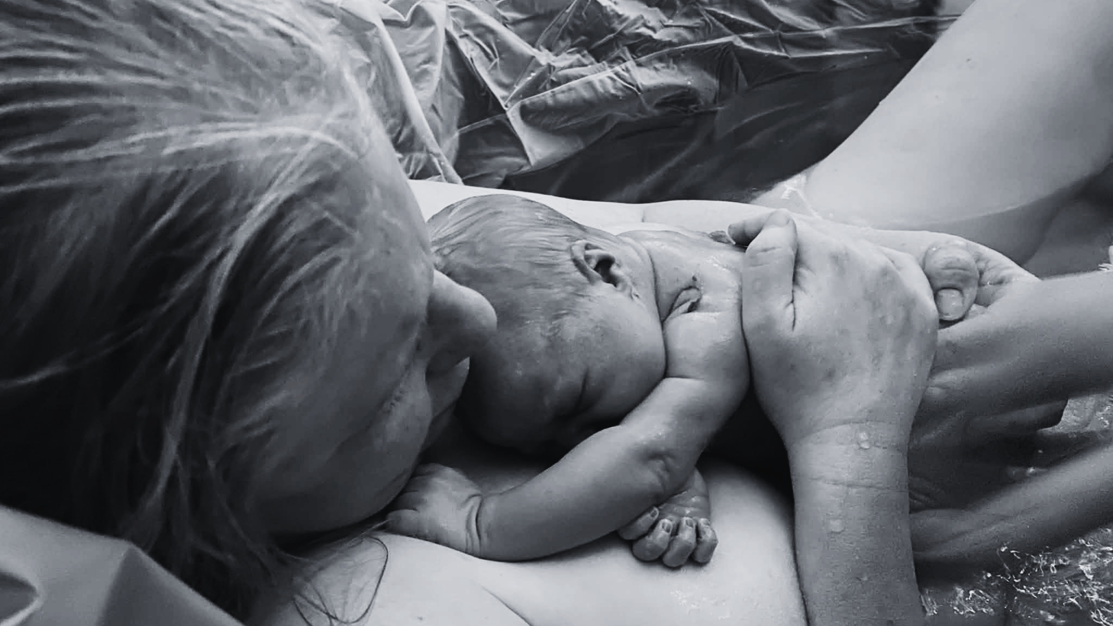 A mother cuddling her newborn baby against her chest in a tender embrace.