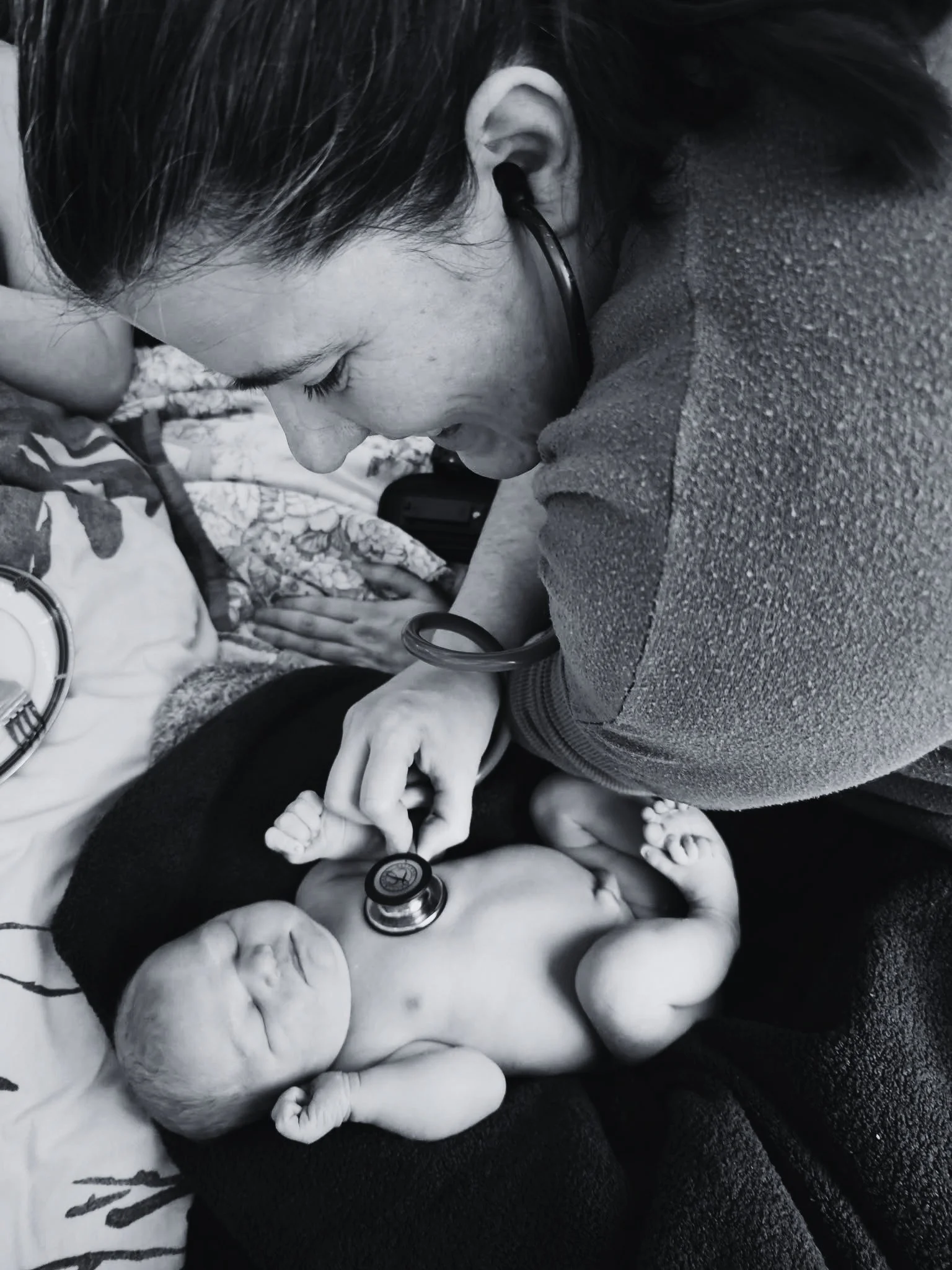 A midwife checking a newborn baby’s heartbeat following delivery.