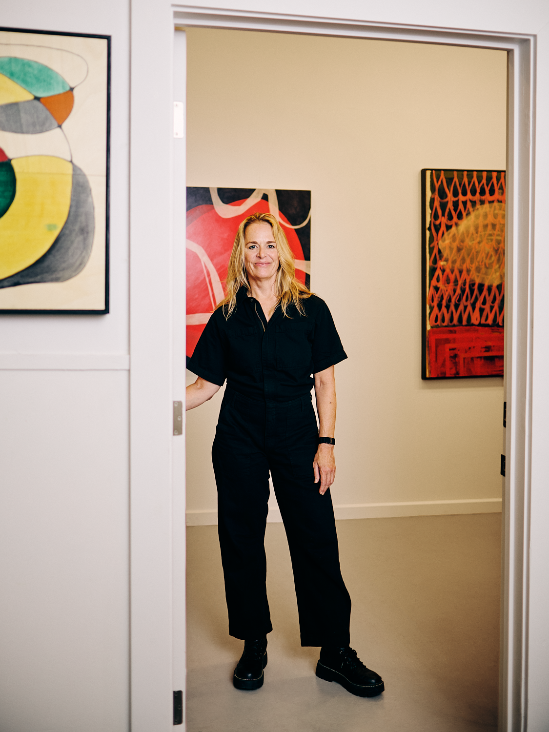 Cathryn Lynea standing in the doorway of her Sausalito studio at the Industrial Center Building (ICB), surrounded by her contemporary abstract and mixed-media paintings.