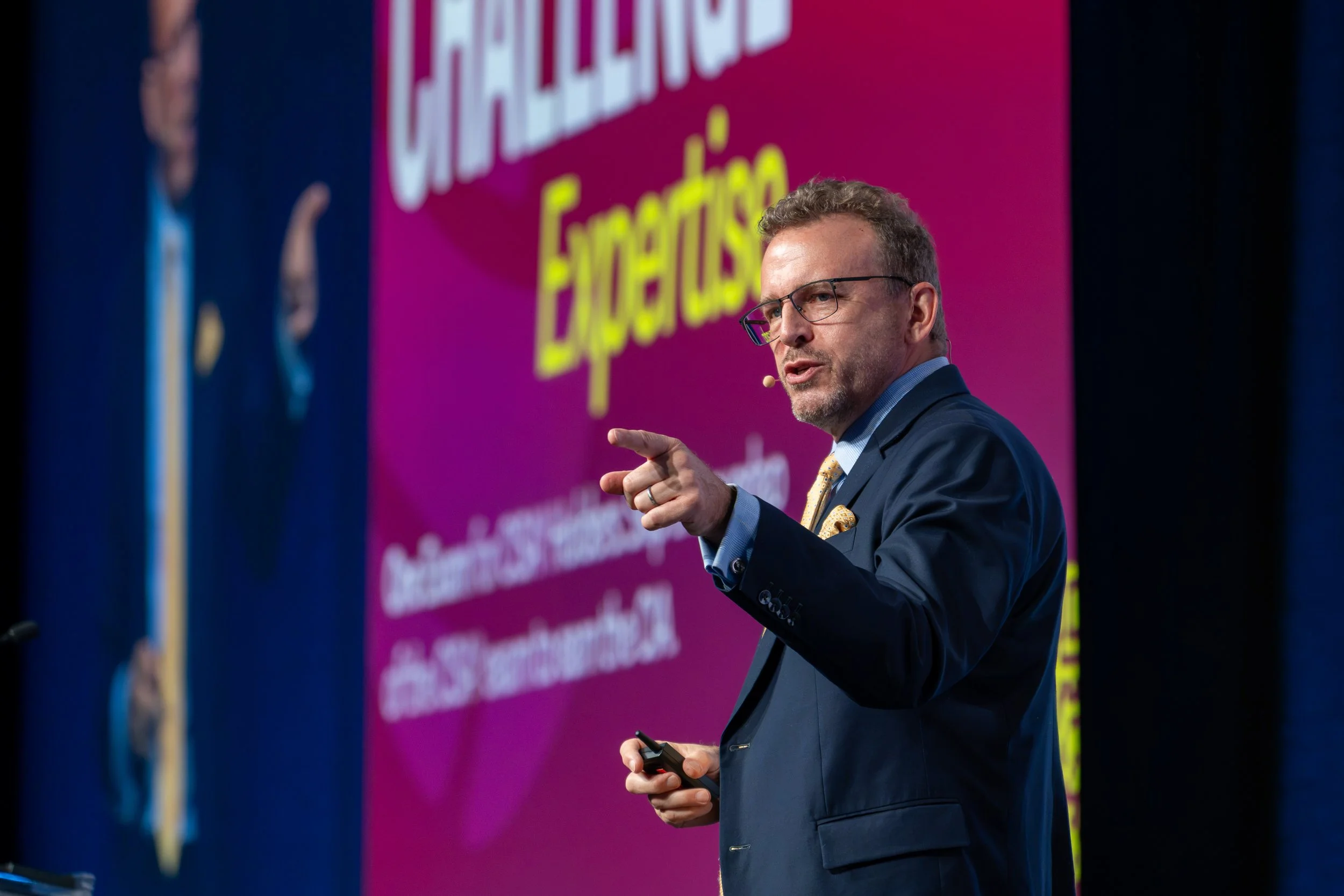 Rob Clark Jr speaking on a large stage with screen in background