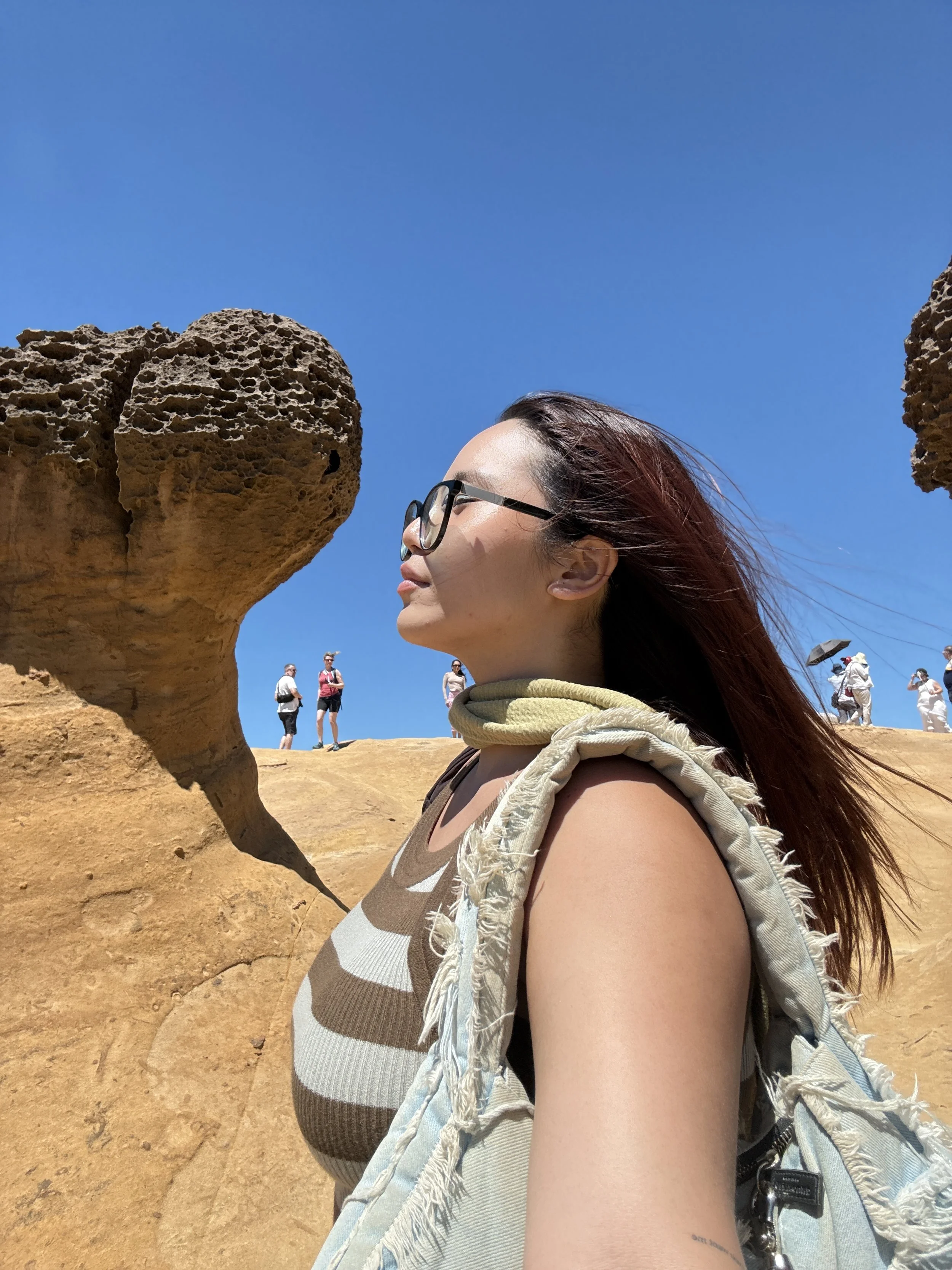 singaporean travel content creator who is looking wistfully into the distance in yehlio geopark, taiwan