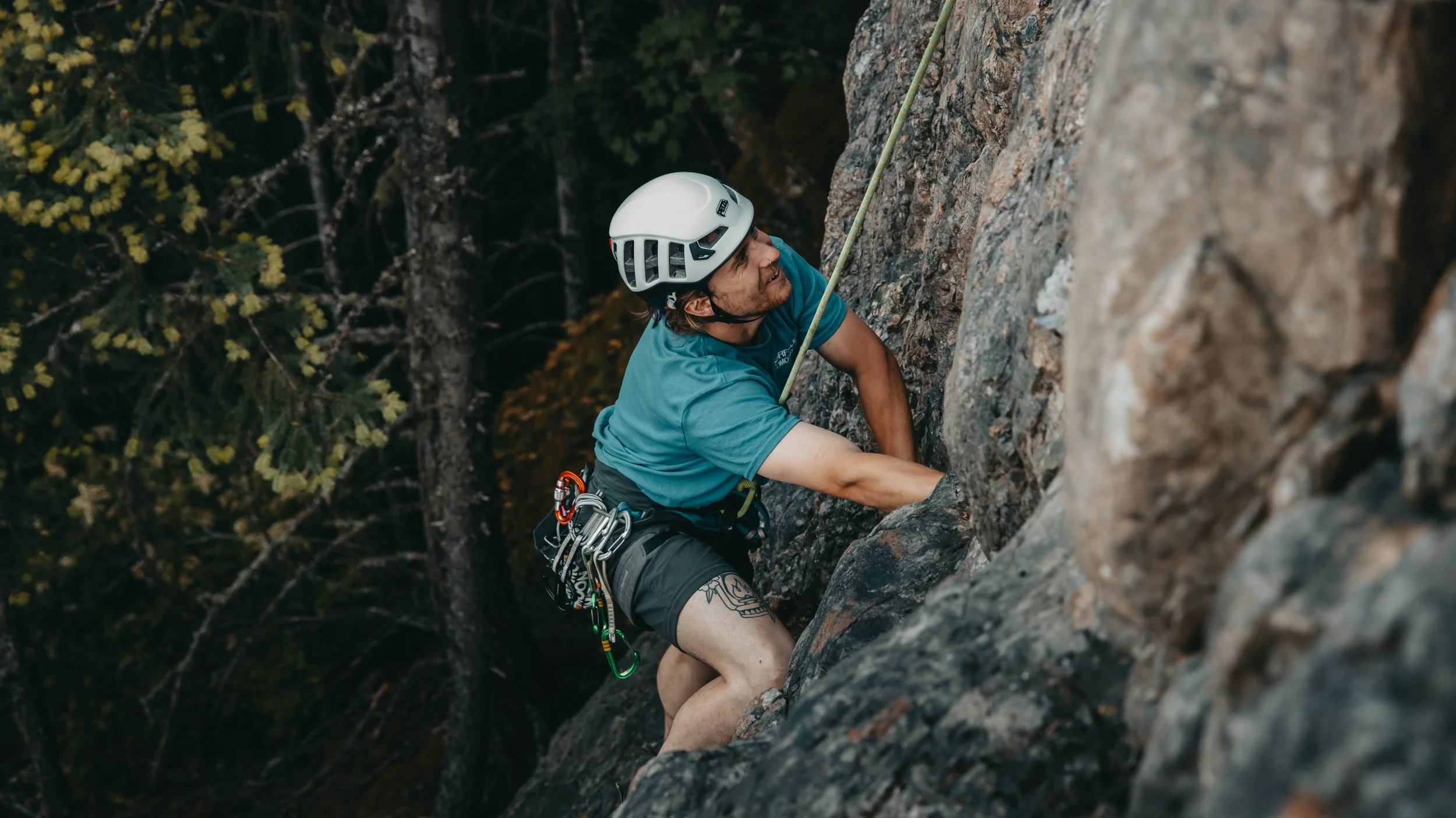A man in a blue shirt rock climbing on Mount Benson, Vancouver Island British Columbia