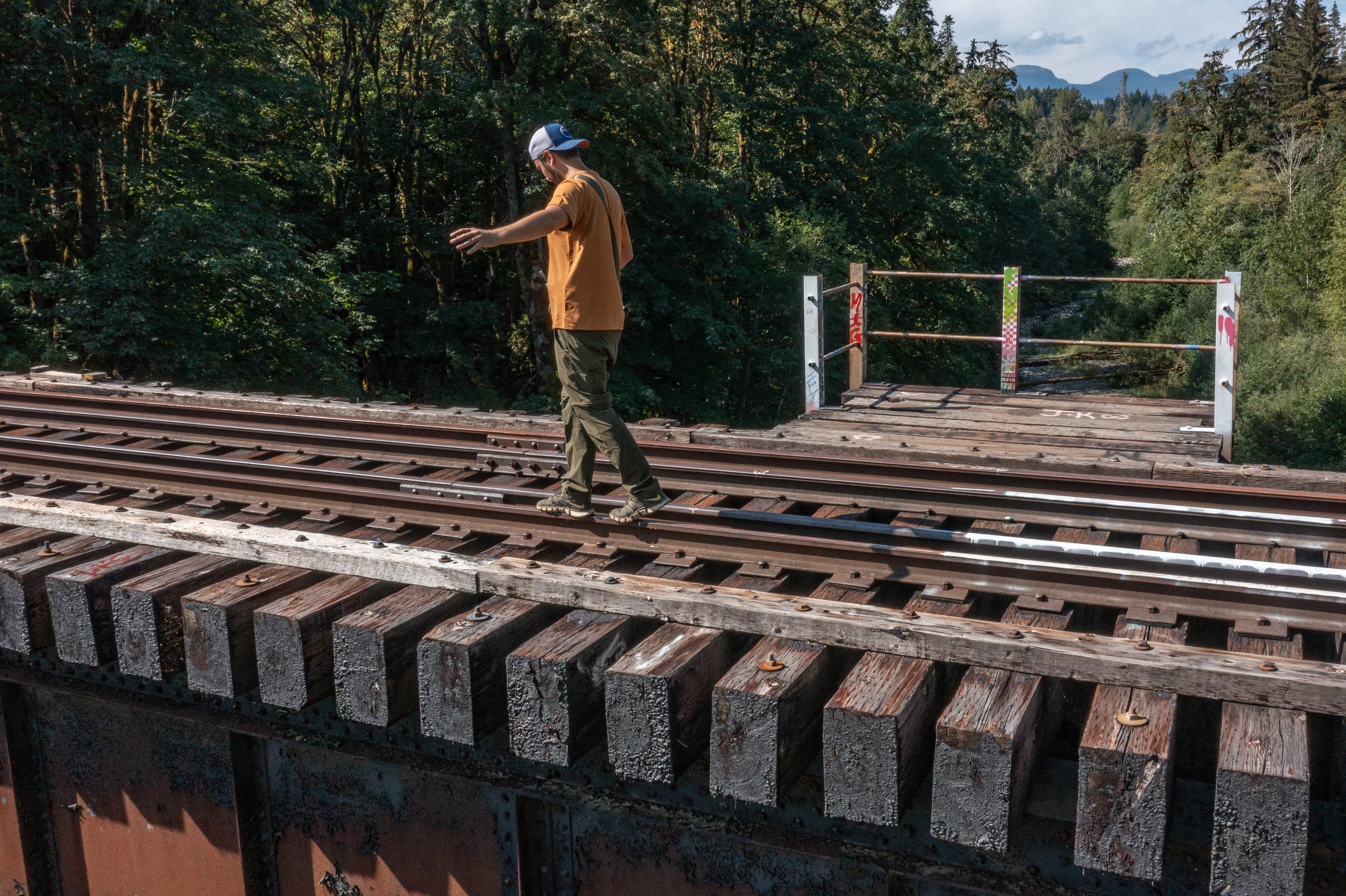 man balancing on the train tracks while crossing the Trent river trestle, Royston BC, Dylan Phillips Photography