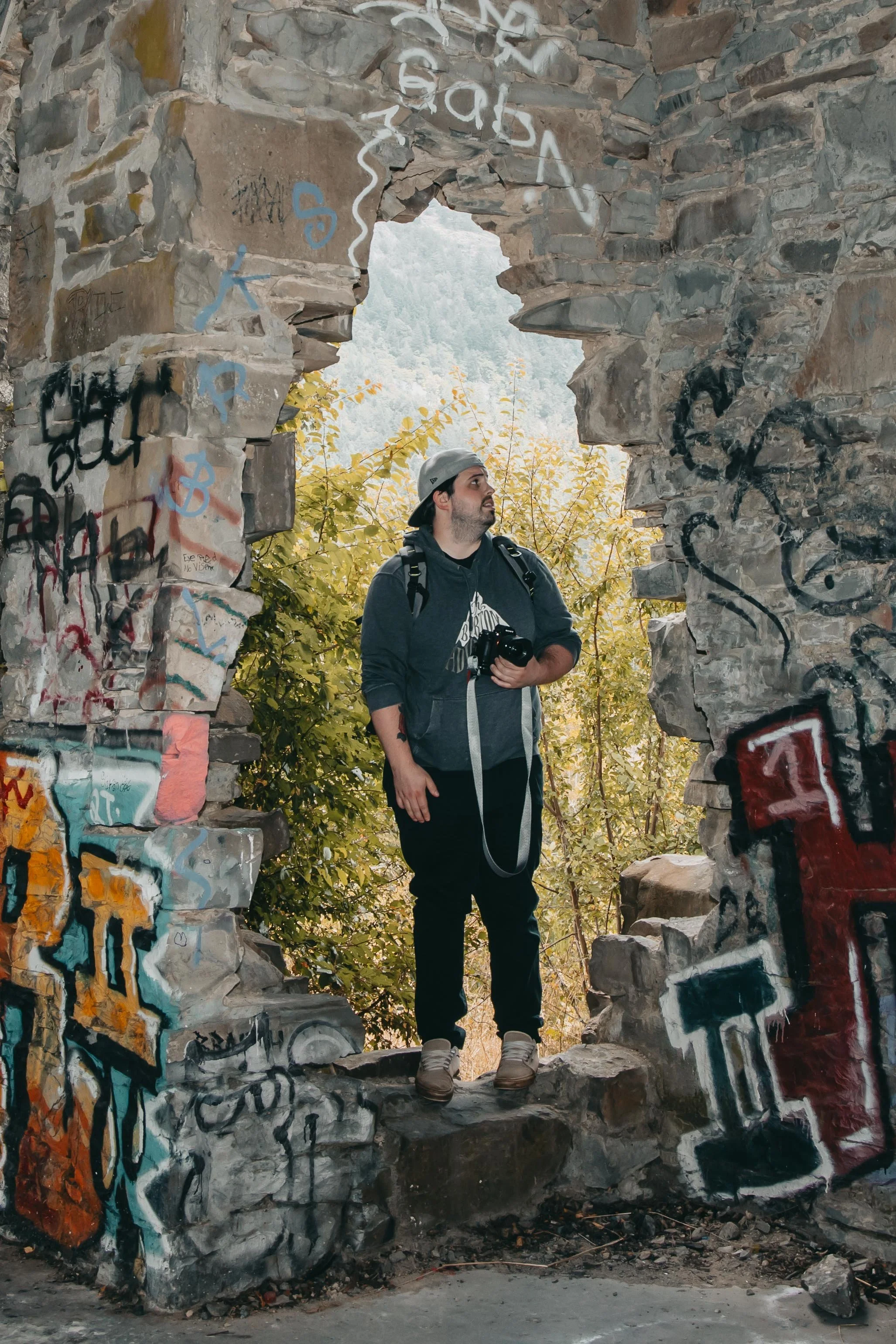 Man holding a camera standing inside the butter stone church, Duncan British Columbia, admiring the stonework and graffiti photo by Dylan Phillips Photography