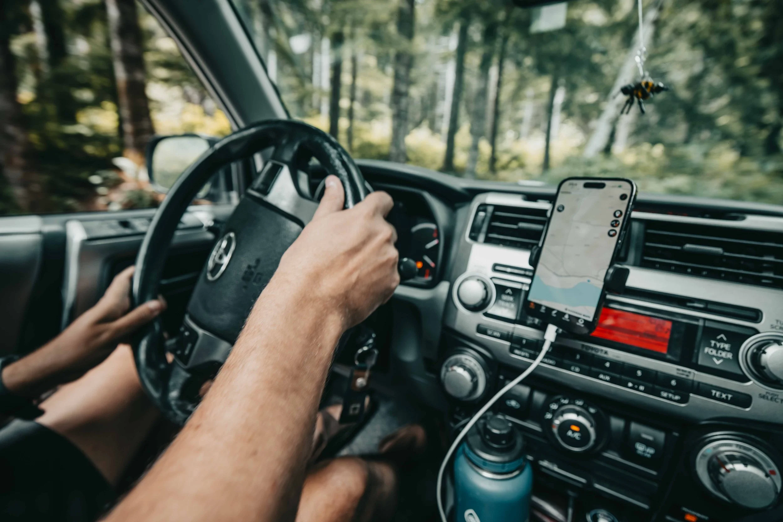 interior of a mand driving a toyota 4runner off road with a iphone displaying navigation
