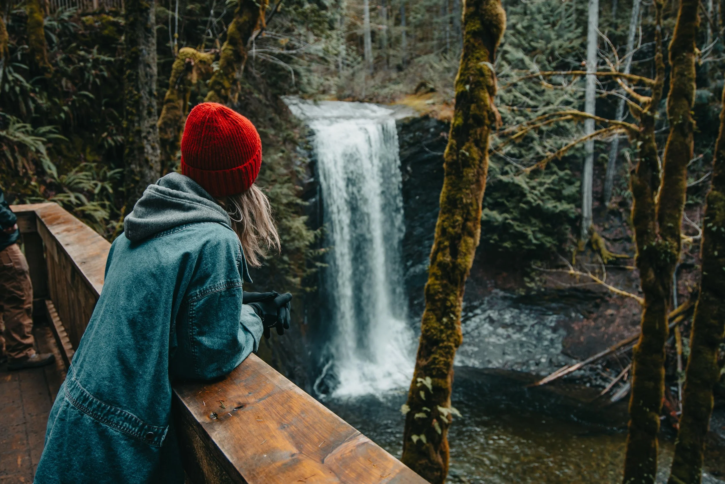 a woman in a red beanie looking out at a waterfall, Ammonite Falls, Nanaimo, British Columbia