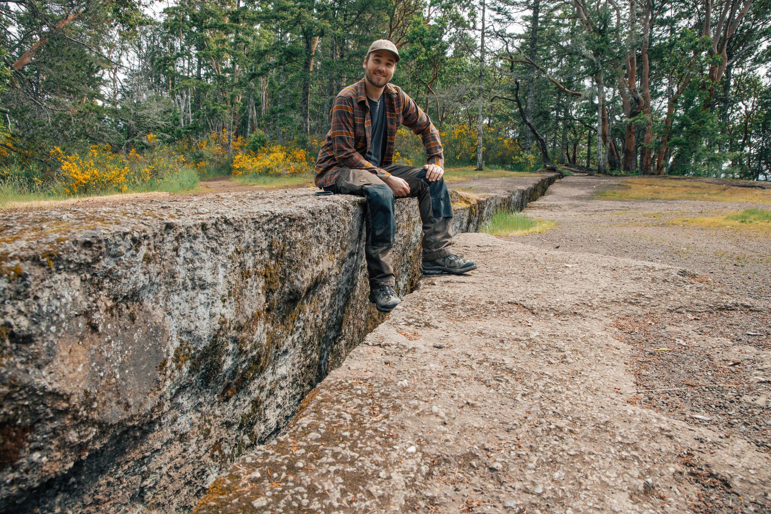 Adventure portrait taken at The Abyss in Nanaimo, BC, featuring a person seated on the rocky ledge beside the famous crack in the ground.