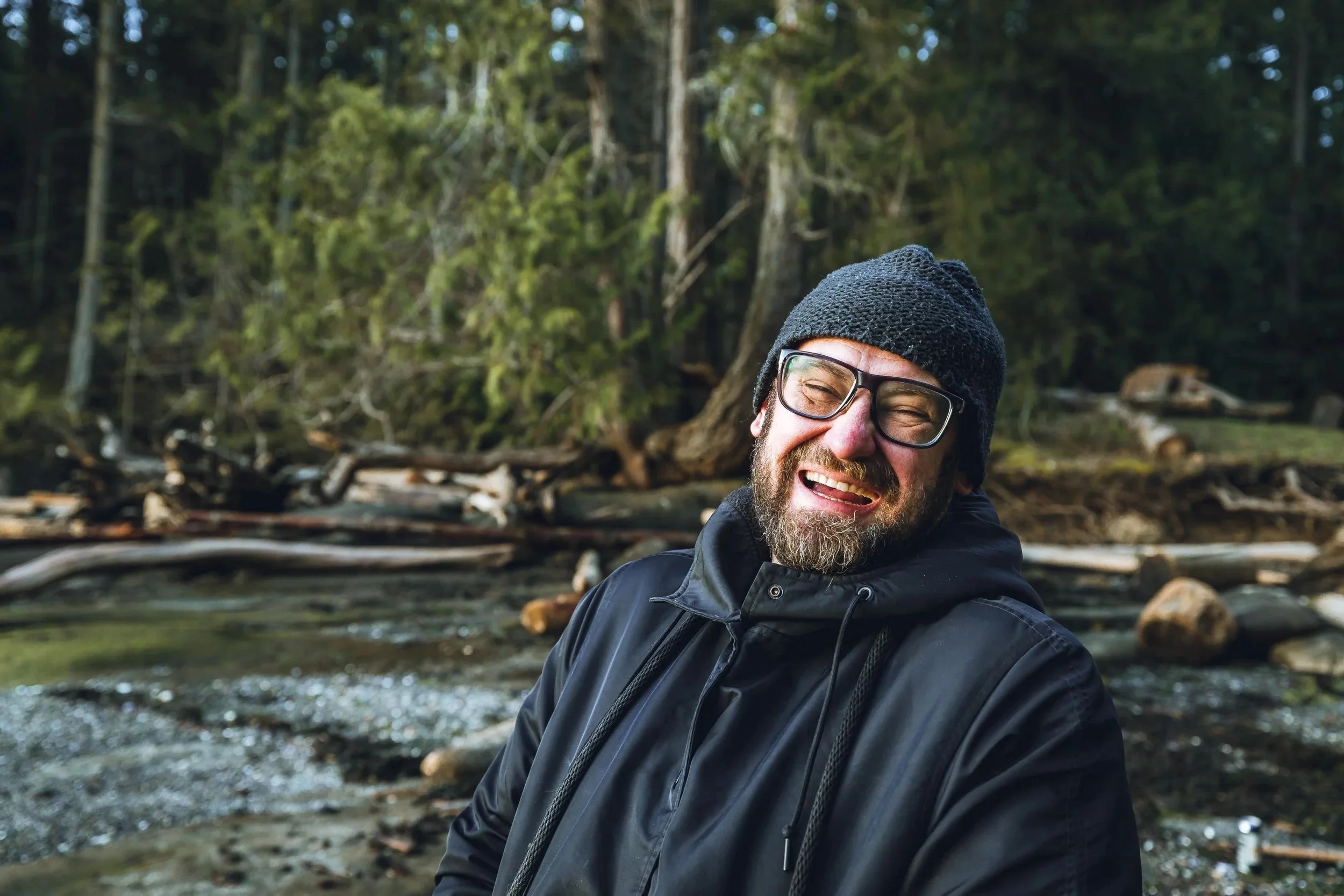 portrait of a man with glasses and a black beanie laughing at the beach, Gabriola island, British Columbia