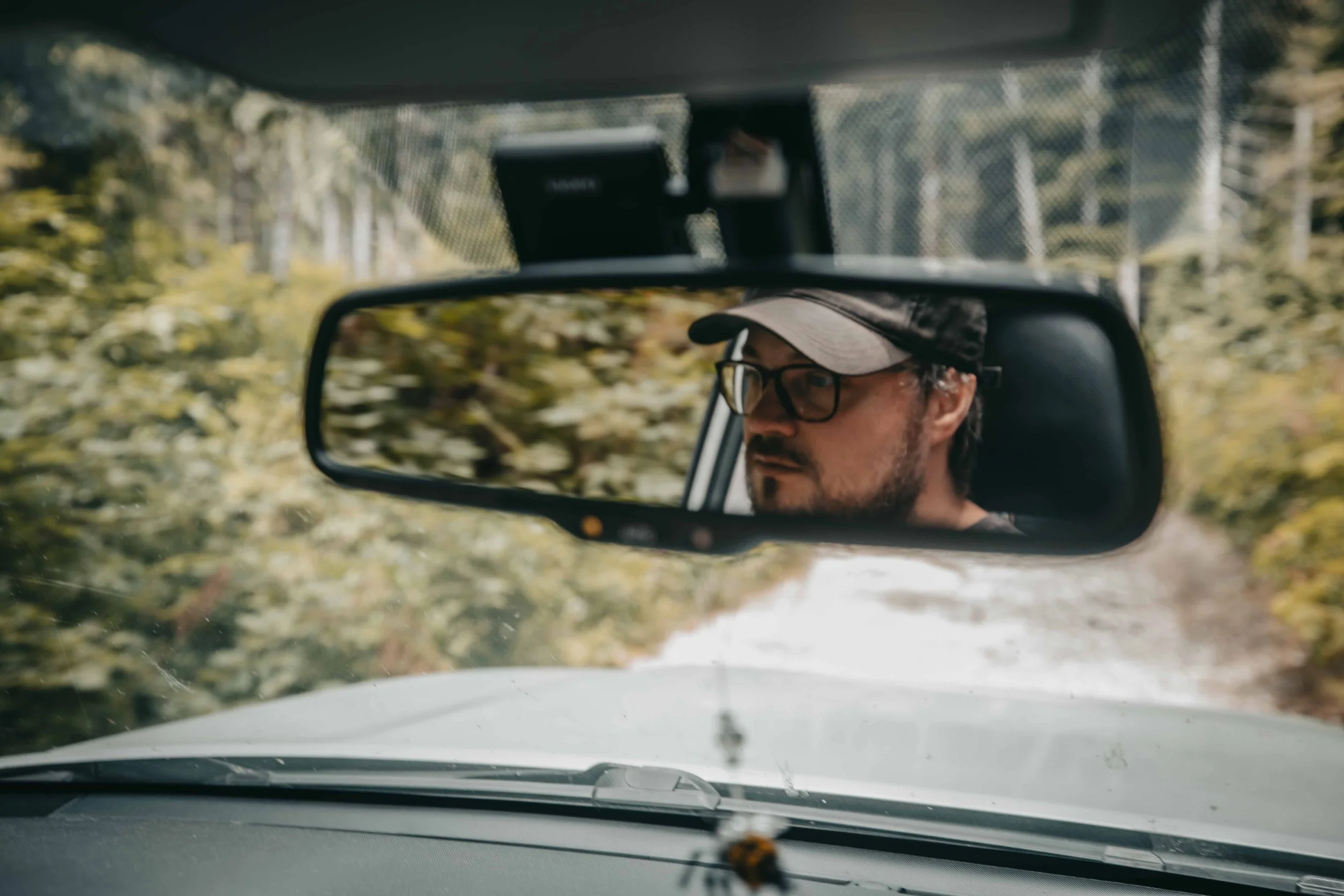 reflection of a mans face in the rear view mirrow of a toyota 4runner driving offroad on vancouver island british columbia