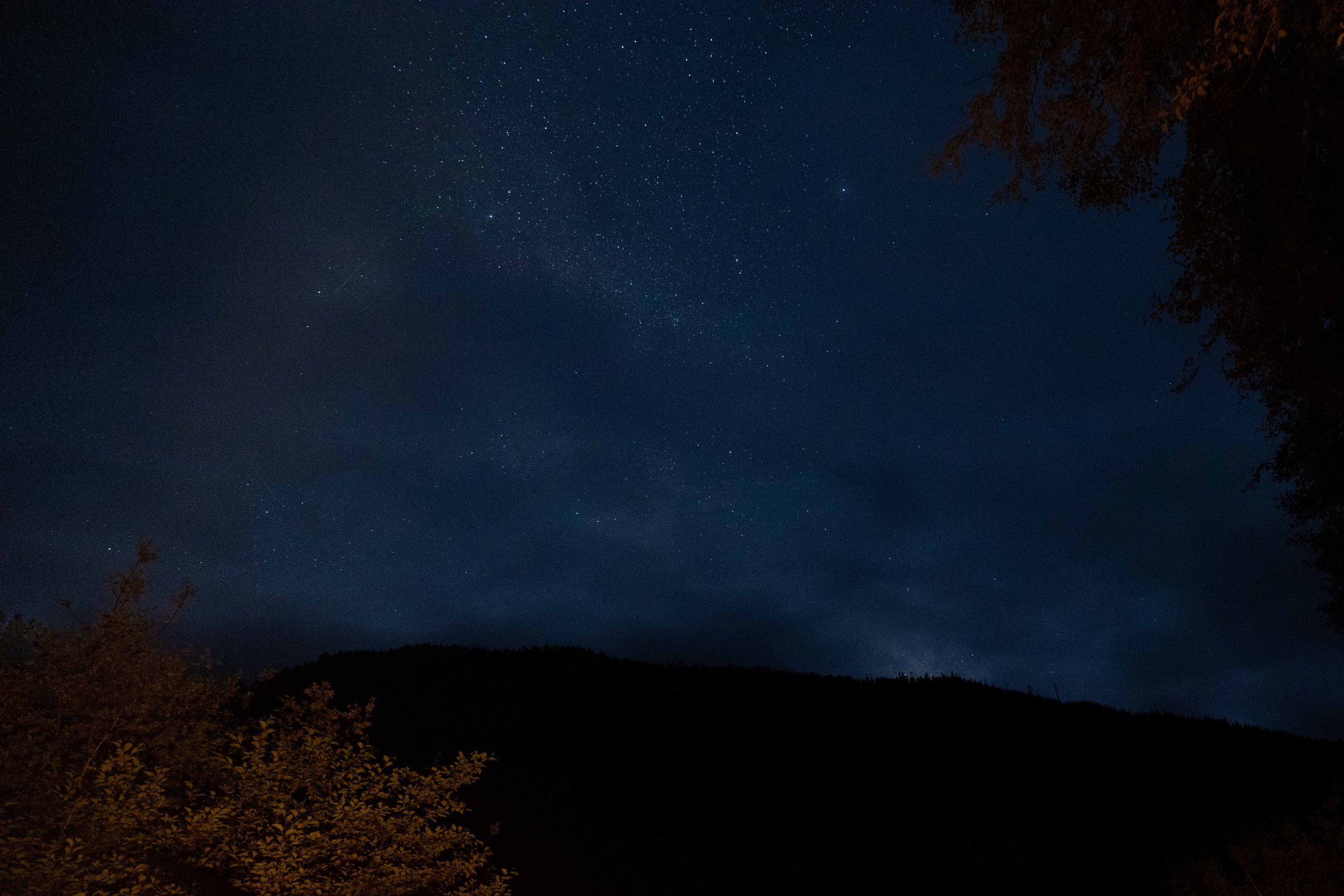 stars dot the night sky over the lake and mountains in background on vancouver island british columbia