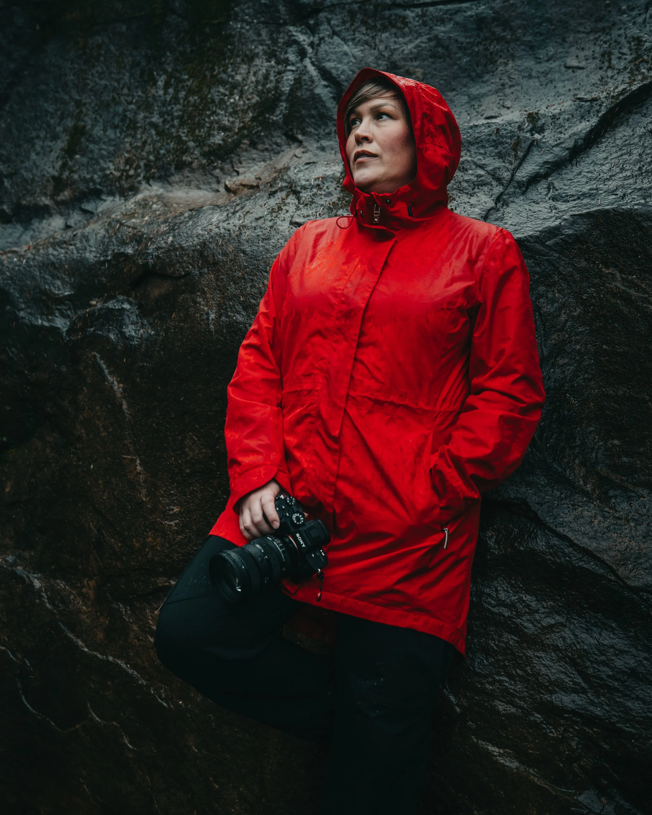 portrait of a woman in a red jacket holding a Sony camera in the rainforest of Vancouver Island