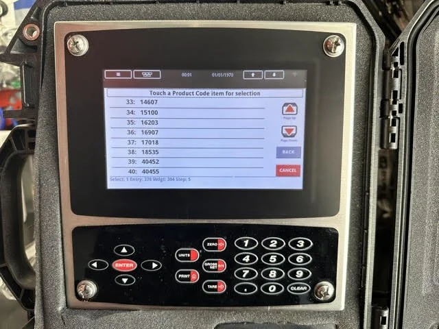 A screen on an electronic device displaying a list of product codes with options to select, cancel, or go back, surrounded by buttons for number input and control.