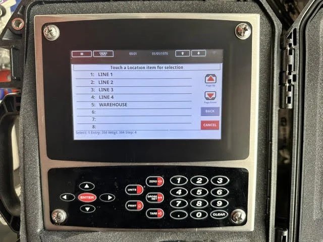 A digital control panel with a touch screen and keypad used for transportation or warehouse management, displaying a list of location options including LINE 1, LINE 2, LINE 3, LINE 4, and WAREHOUSE.