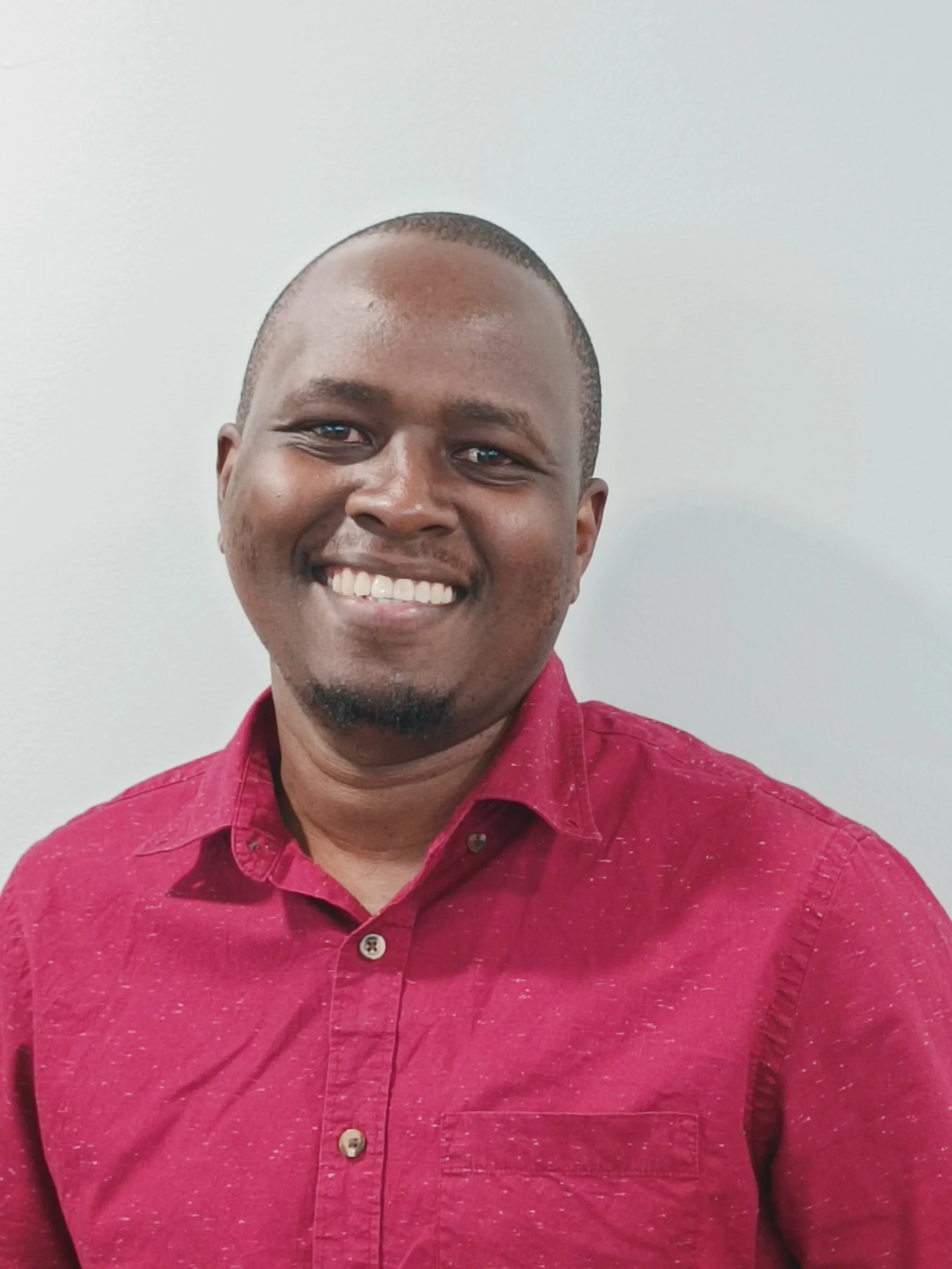 Smiling person wearing a red shirt against a white background.