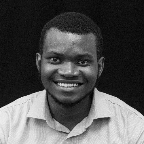 Black and white portrait of a smiling man wearing a light-colored shirt against a dark background.