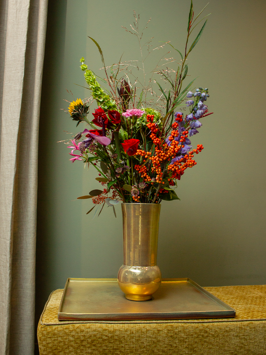 Een vaas met kleurrijke bloemen, geplaatst op een tafel.