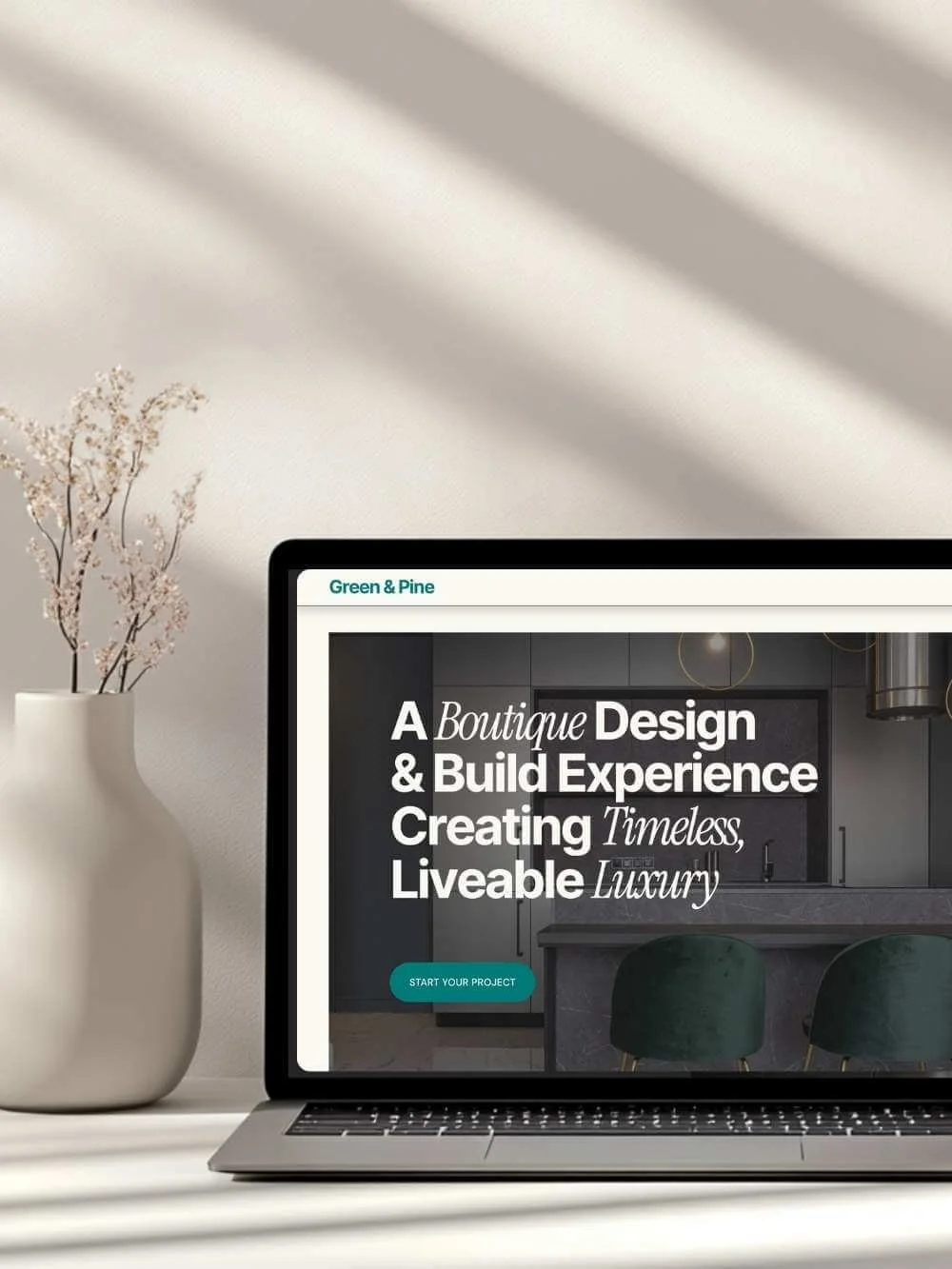 Laptop screen displaying a custom builder/architecture website template. The hero image features a high-end kitchen interior with bold white text: "A Boutique Design & Build Experience Creating Timeless, Liveable Luxury" and a teal call-to-action but