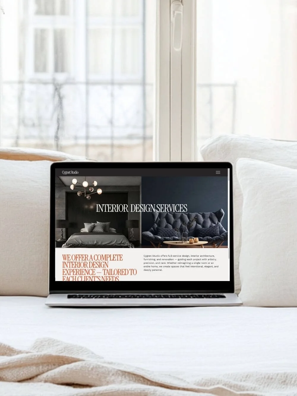 Laptop displaying the “Cygnet Studio” website template’s "INTERIOR DESIGN SERVICES" page. The text on the screen highlights that the studio offers a complete interior design experience tailored to each client's needs.