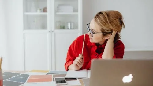 A small business owner sitting at a desk, brainstorming website goals with a notepad, colour swatches and minimalist decor.