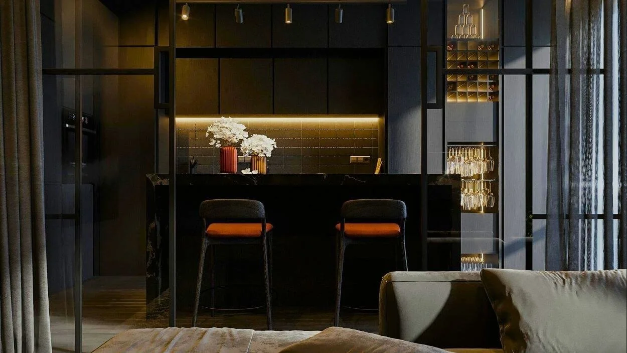 Close-up of a high-end, dark, modern kitchen or bar area featuring black cabinetry, subtle under-cabinet lighting, and two chairs with bright orange seats. There is a decorative glass cabinet for wine and glassware to the right.