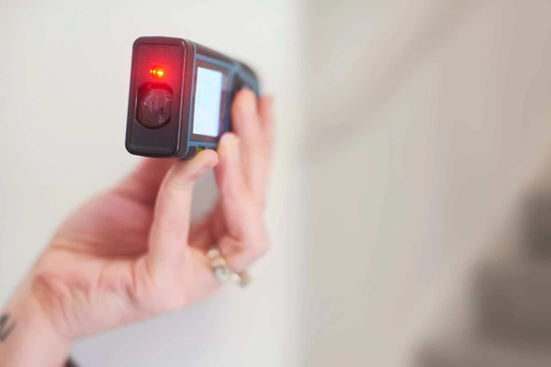 a hand holding a digital laser measuring device