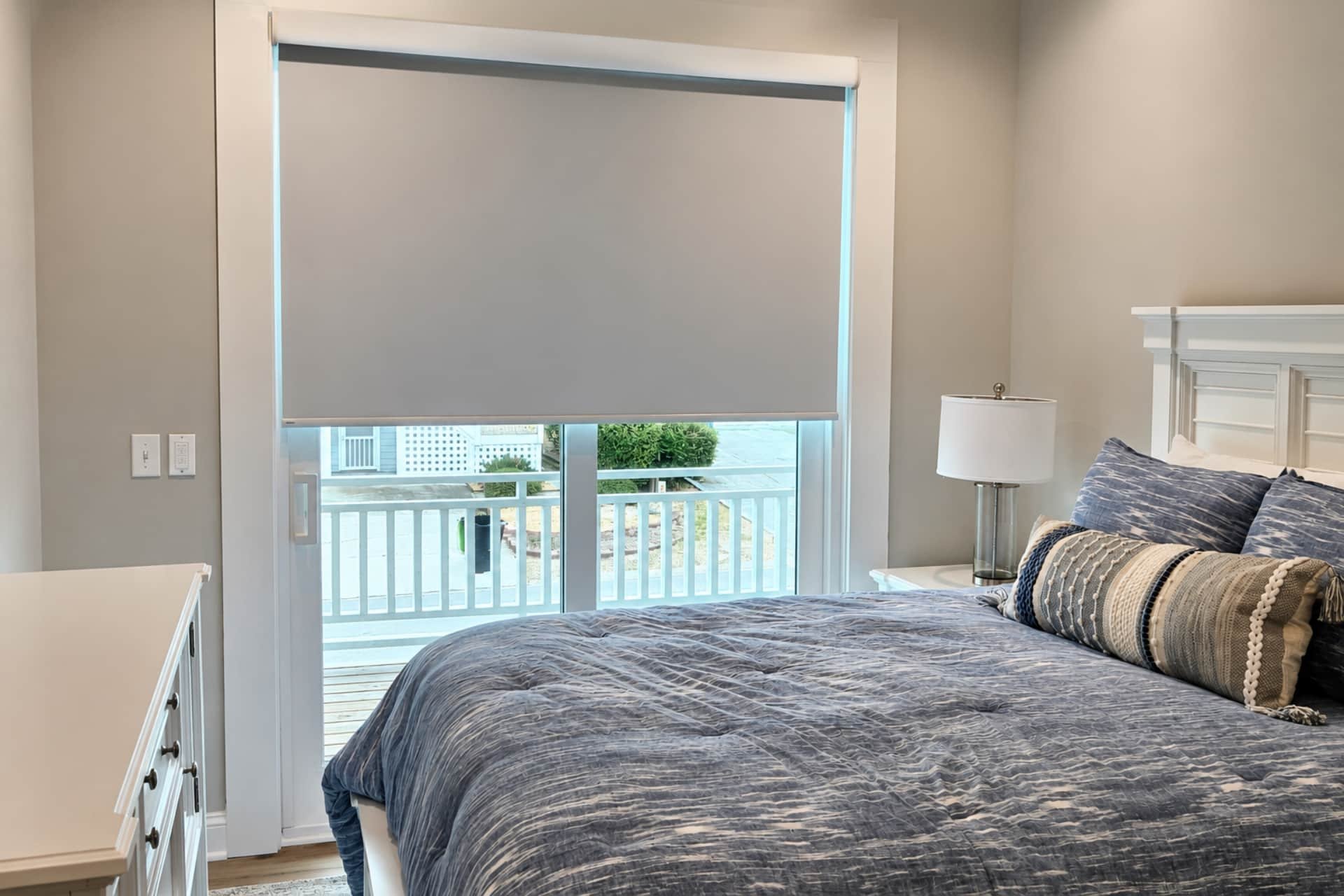 bedroom with a large window facing the street with a roller shade