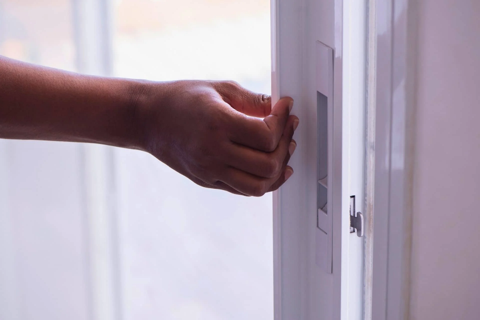 a hand opening a sliding glass door
