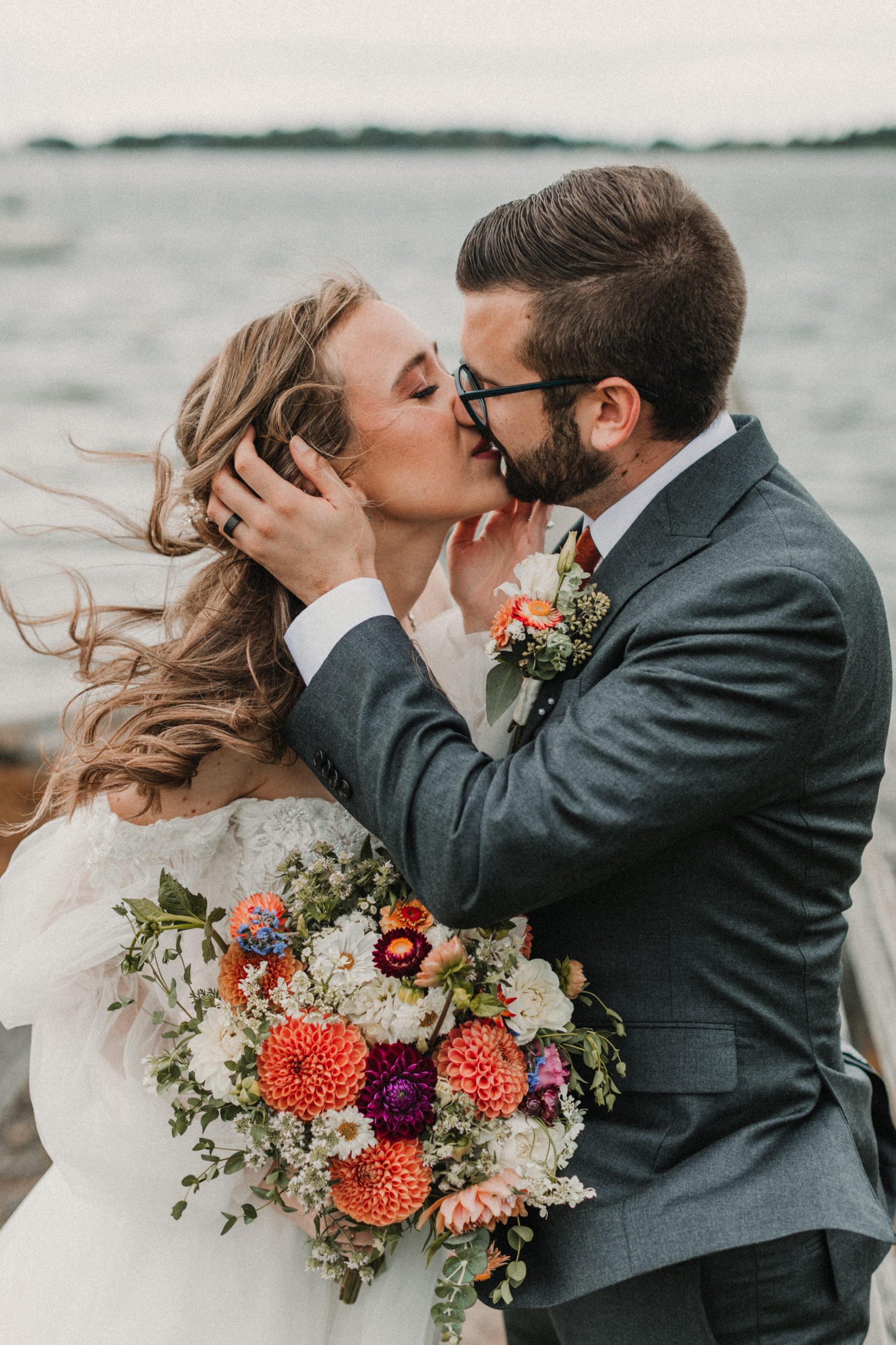 bride and groom kissing during ceremony in front of water at destination wedding