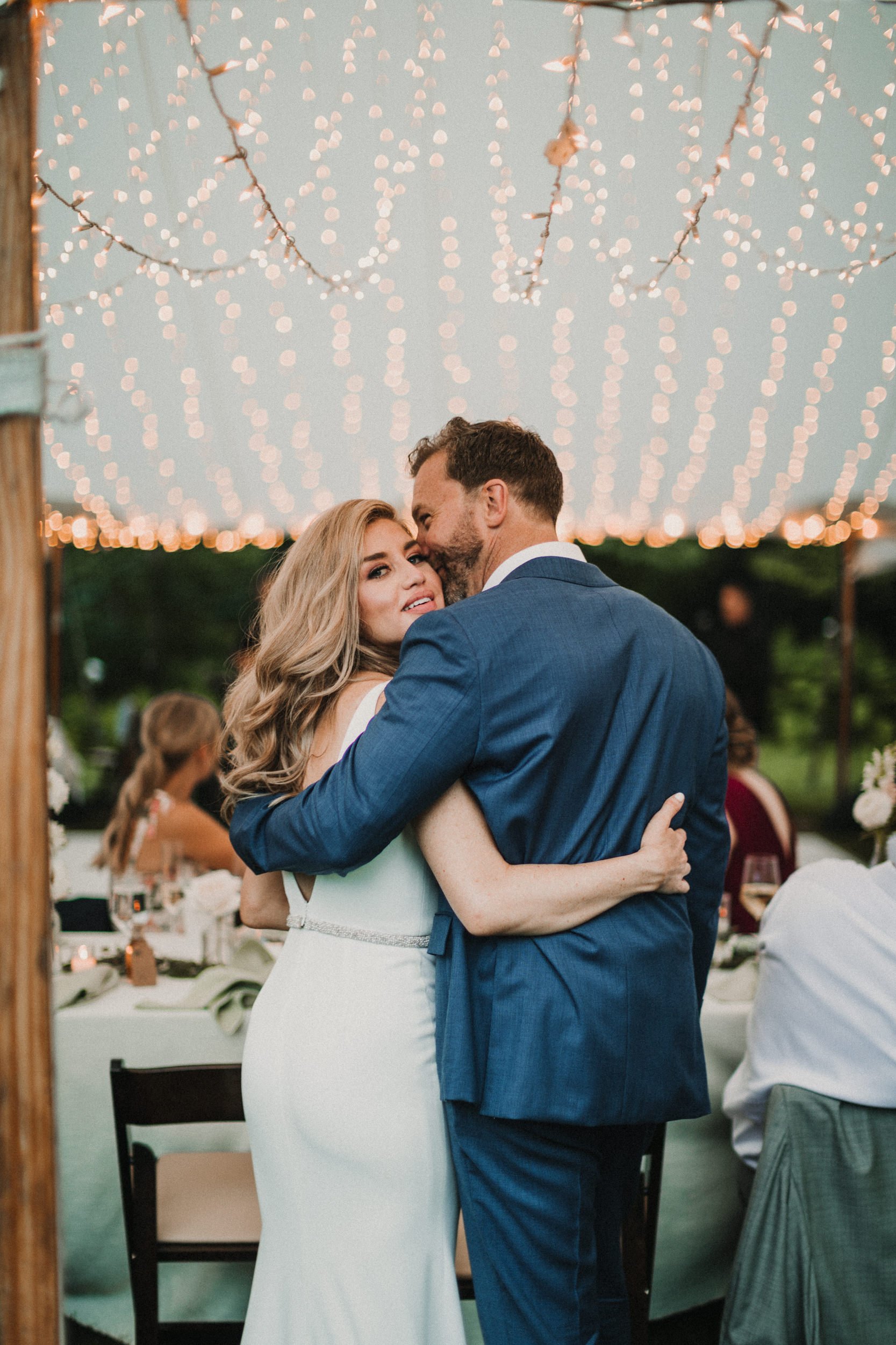 modern bride and groom embracing under twinkle lights in new hampshire