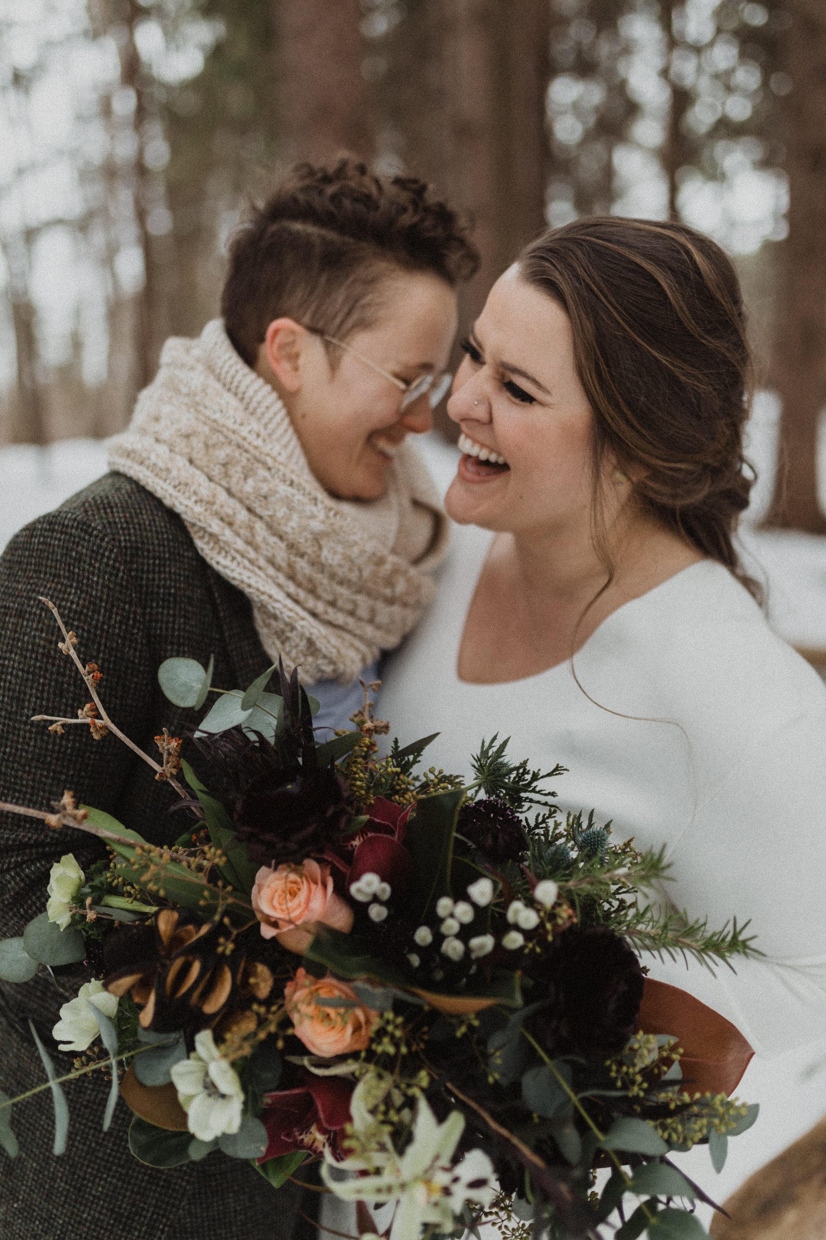 2 woman hugging and laughing during winter wedding in new hampshire