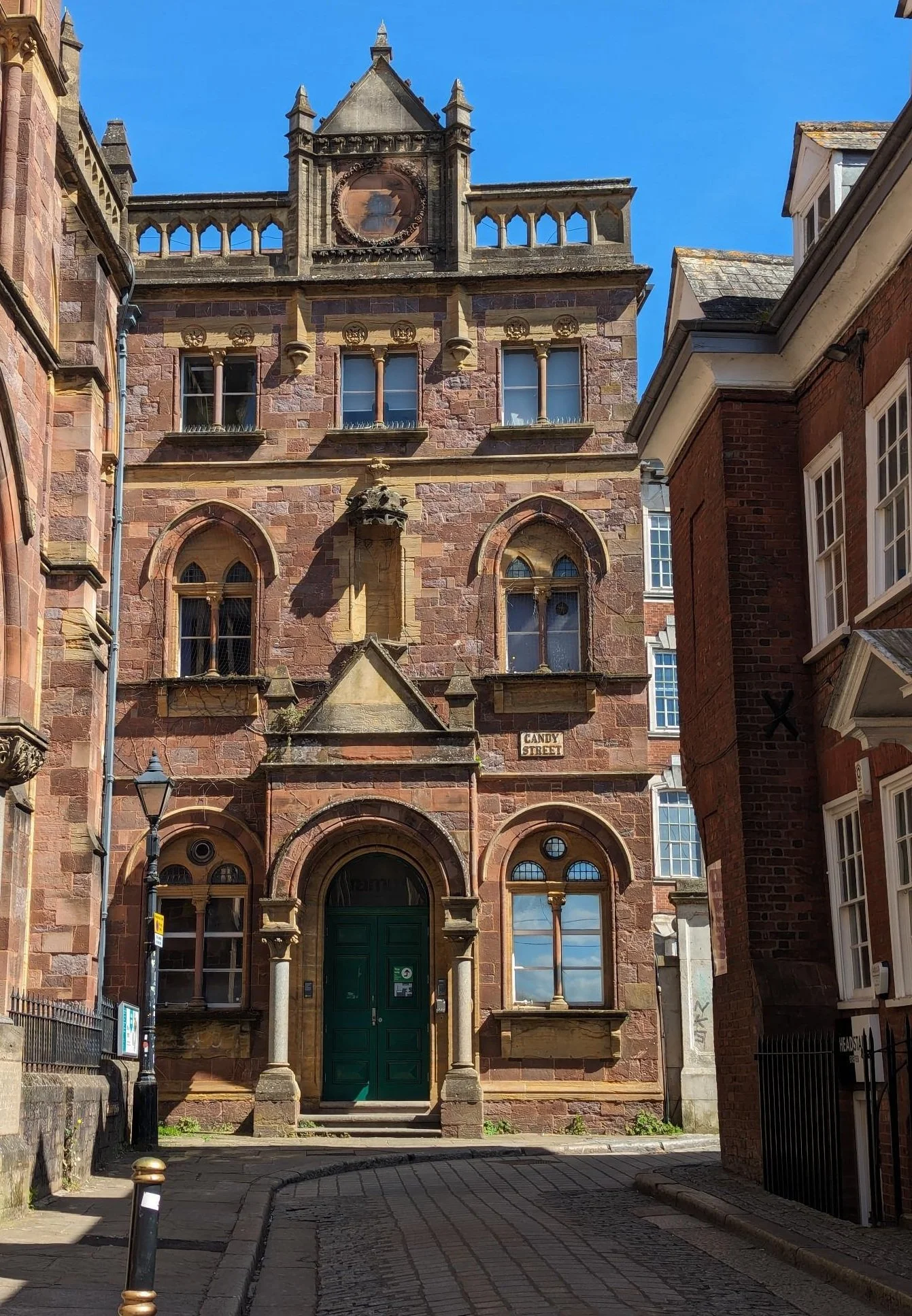An old red-bricked building on a cobbled street with arched doors and windows.