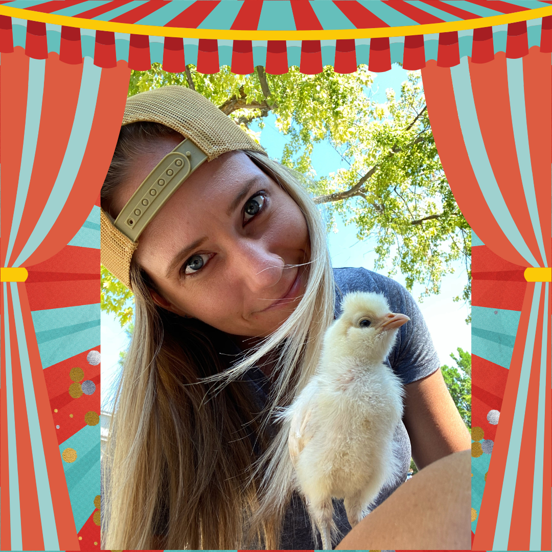 A women smiling into the camera wearing a baseball cap and holding a chick.