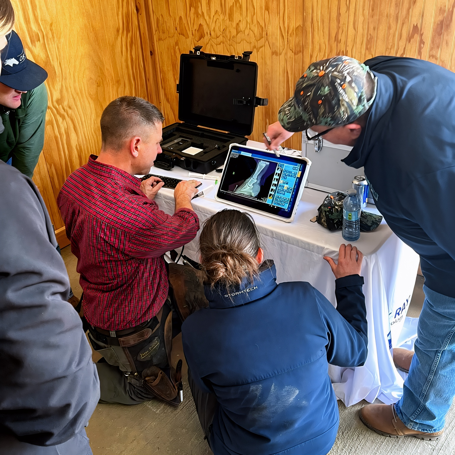 A group of people gathered around a table showing a 3D x-ray of a leg on a computer screen.
