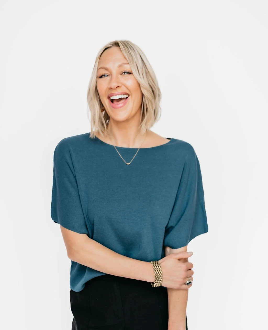 Kristine with a blue blouse and black pants laughing