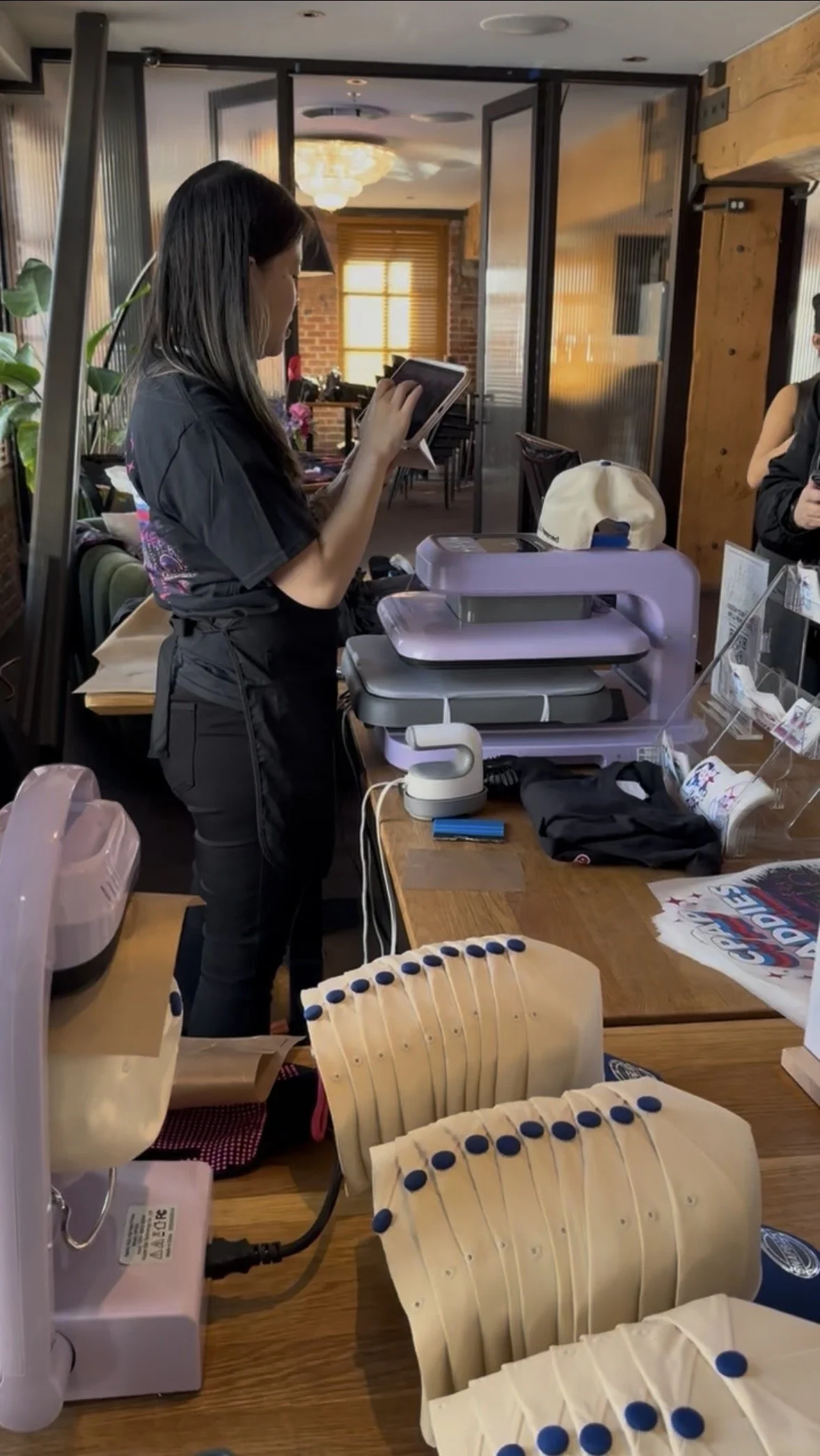 A person operating a heat press machine on a white fabric surface.