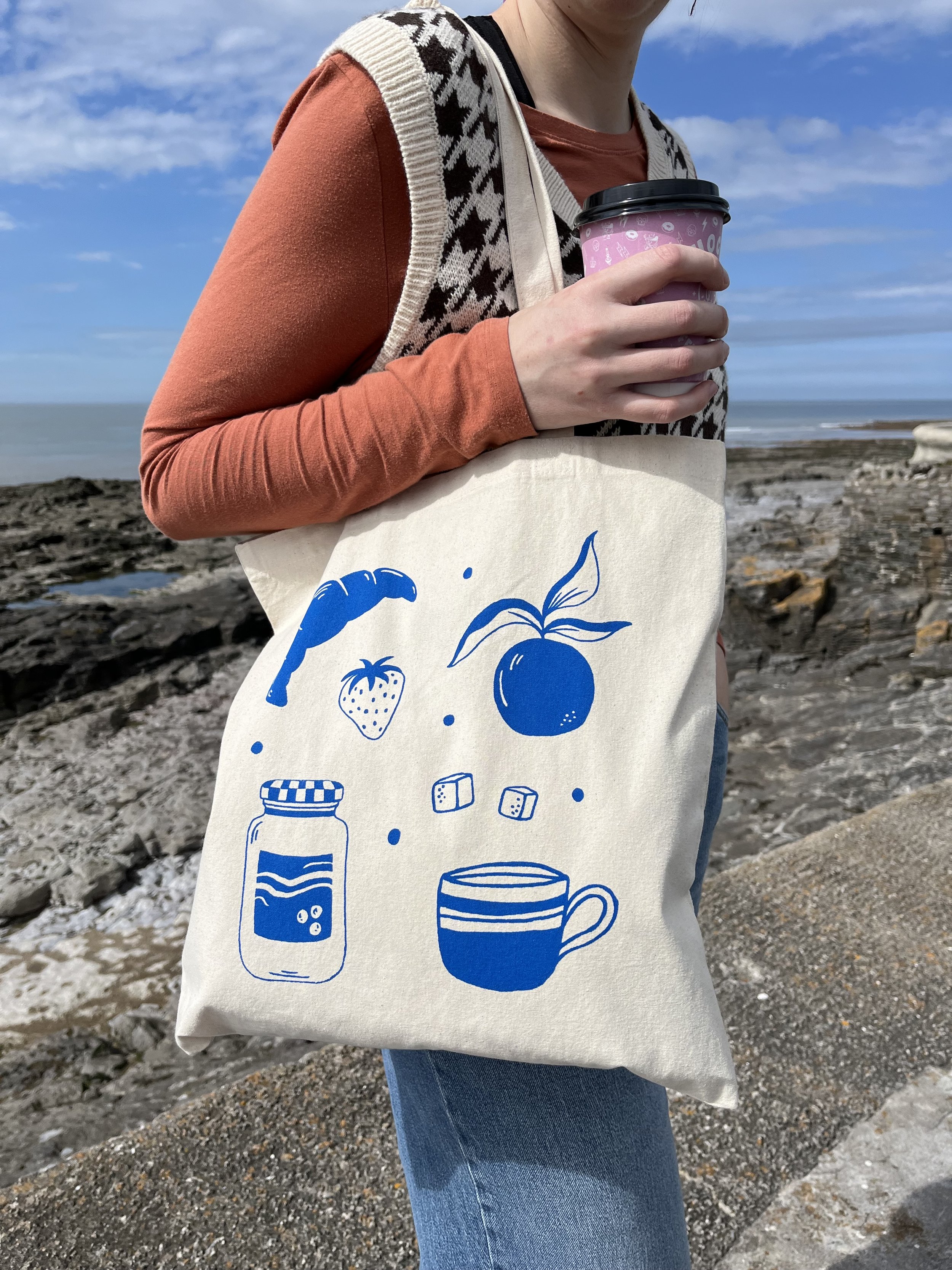 Tote bag featuring croissant, orange, jam, mug and sugar design