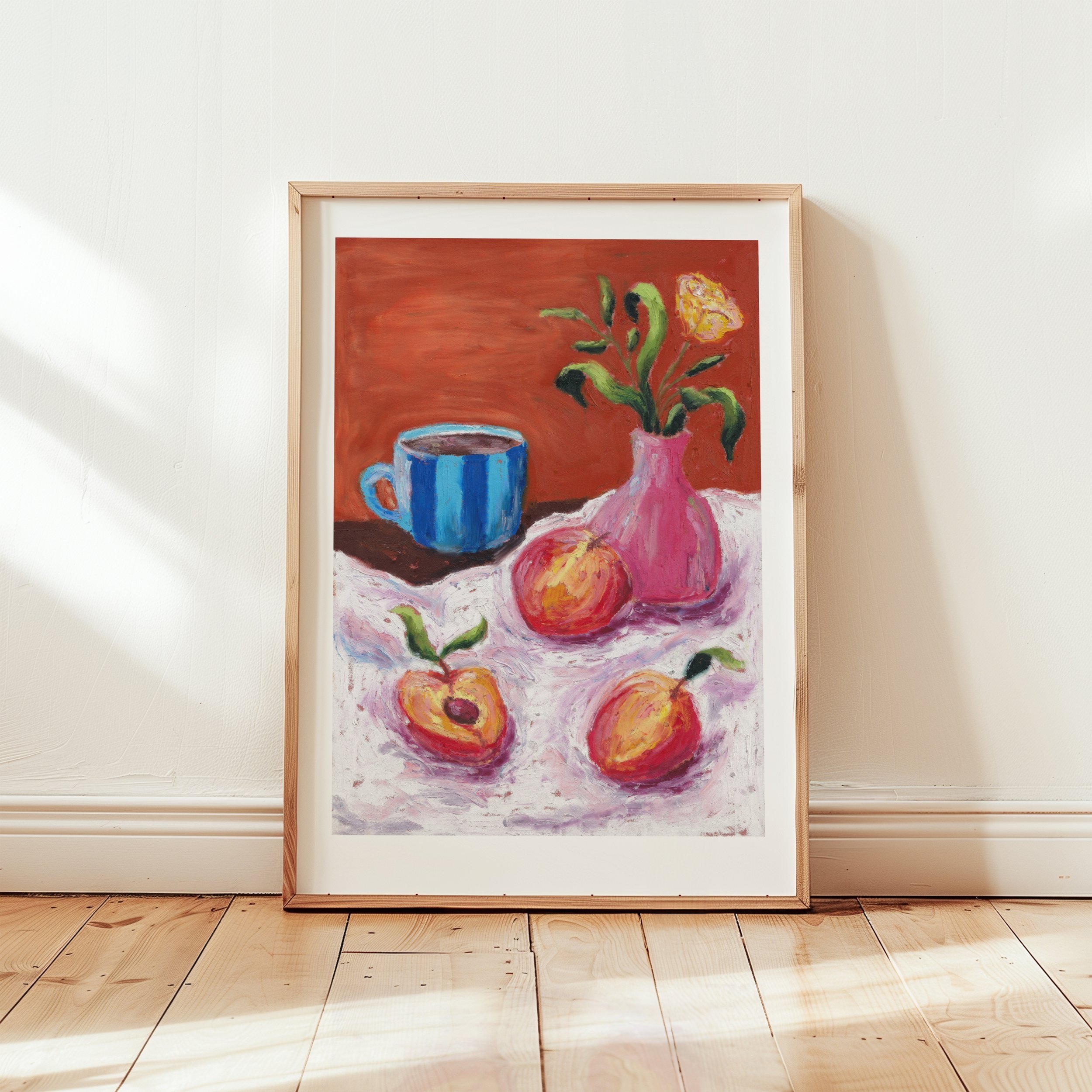 A wooden framed print of an oil pastel painting of peaches, coffee and flowers on a wooden floor