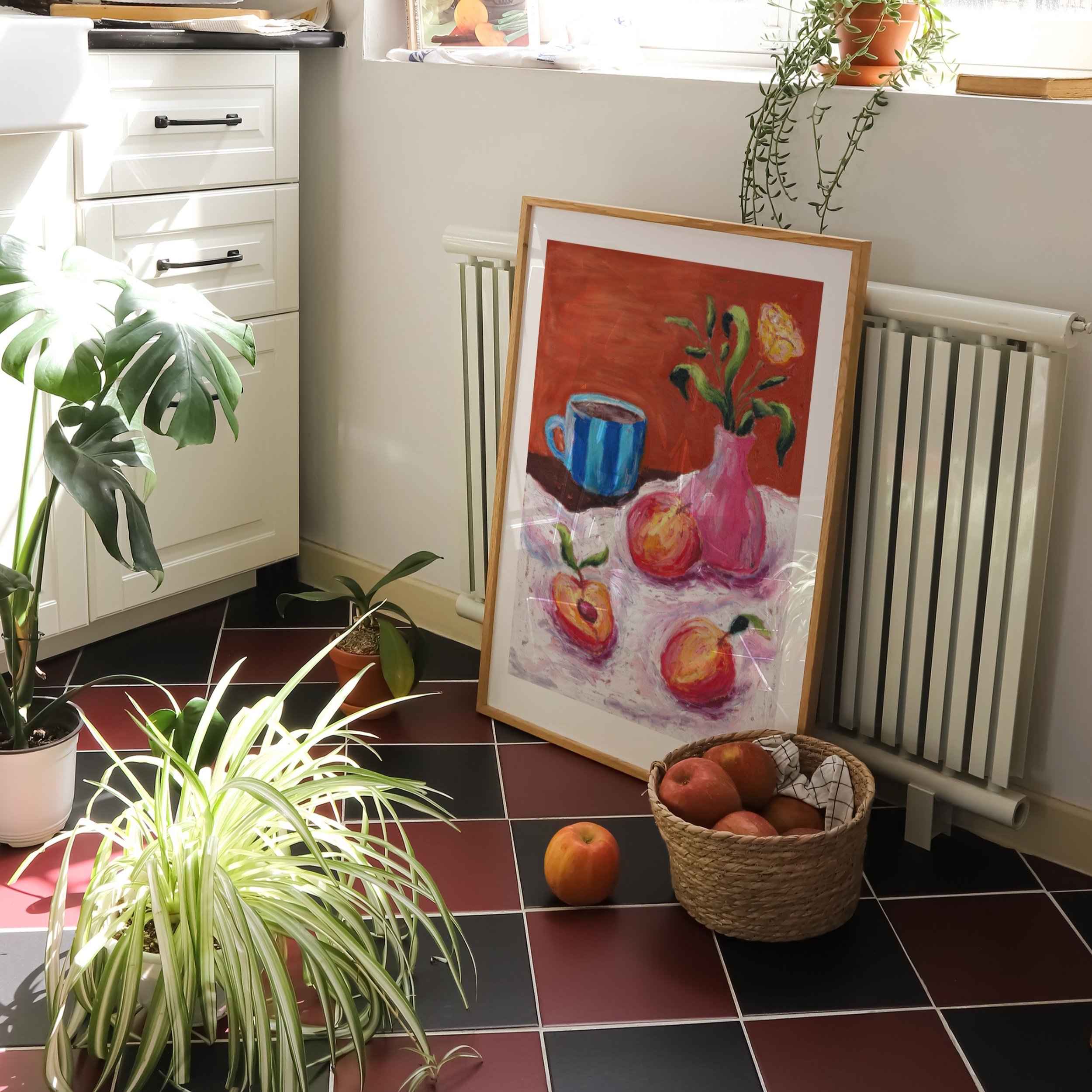 A wooden framed print of an oil pastel painting of peaches, coffee and flowers in a kitchen