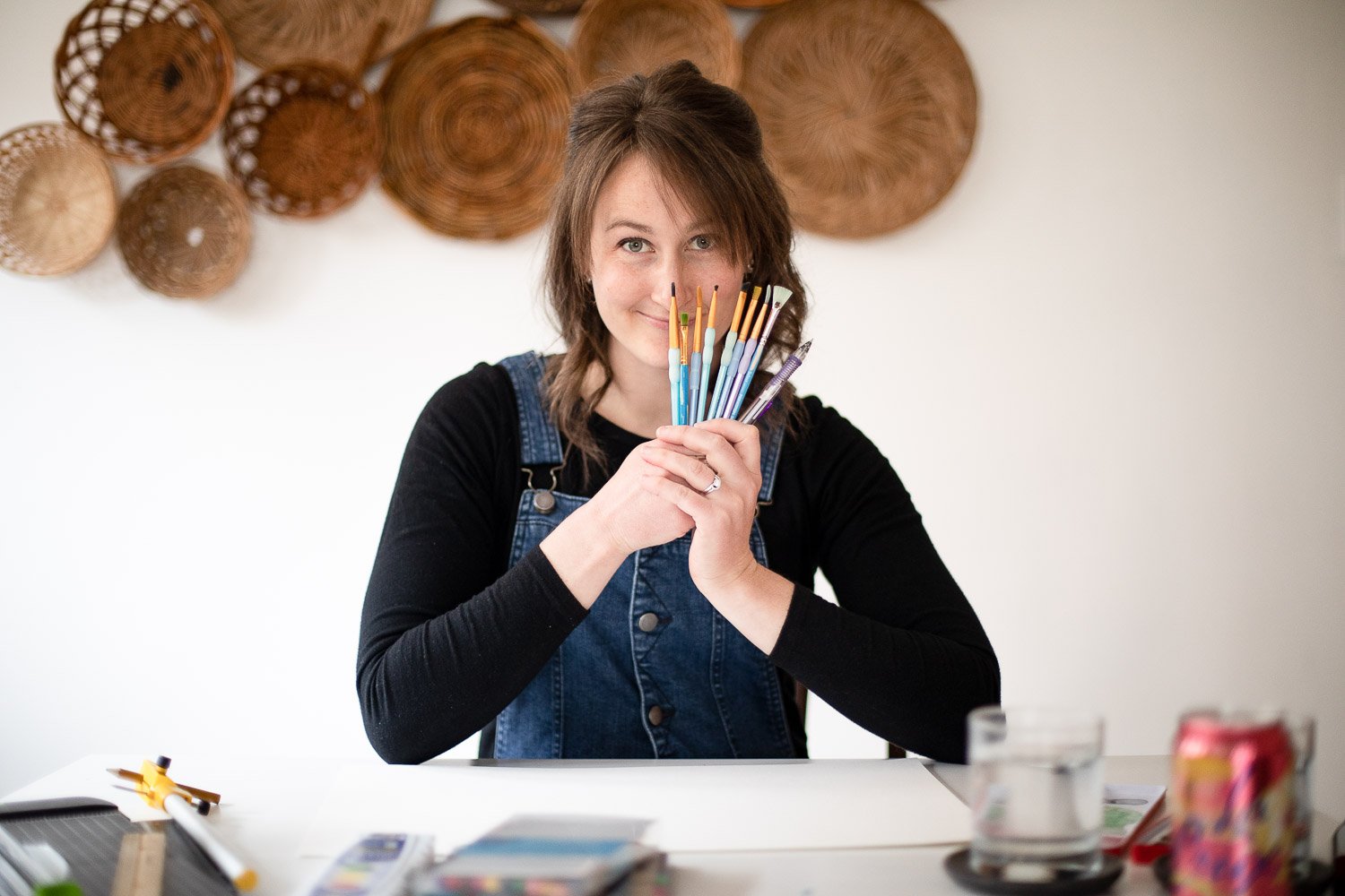 Alison Kroening holding up watercolor paintbrushes