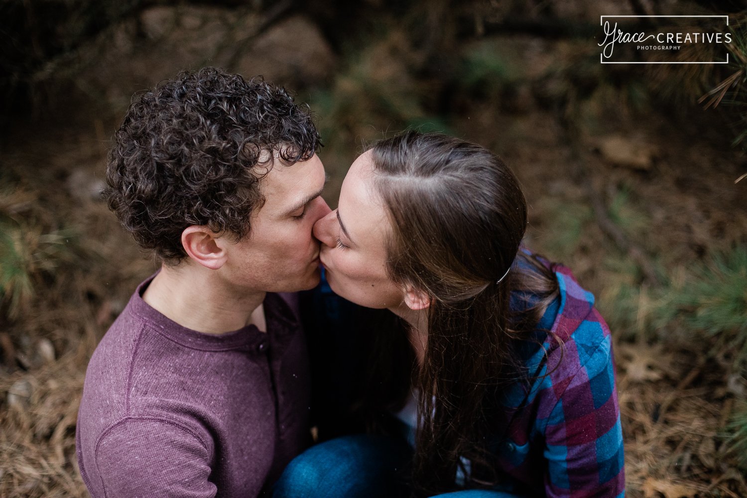 Engaged couple kissing on the ground at the Arboretum during this Madison engagement session