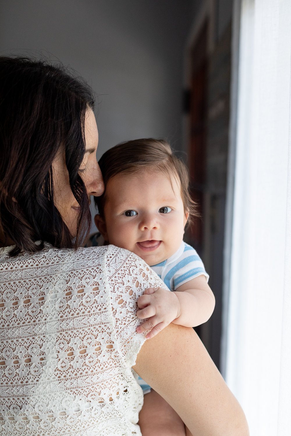 happy baby being held by mom during three month baby photoshoot in milwukaee