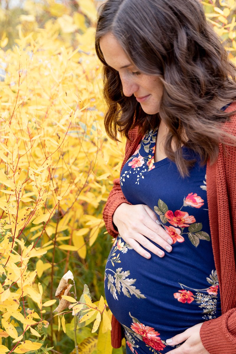 mother looking at her baby bump during a Fall Maternity Session at Fox Brook Park in Brookfield with Grace Creatives photography