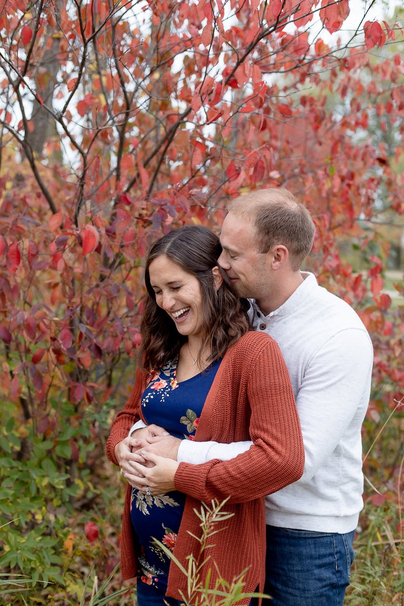 mom and dad laughing during a Fall Maternity Session at Fox Brook Park in Brookfield with Grace Creatives photography