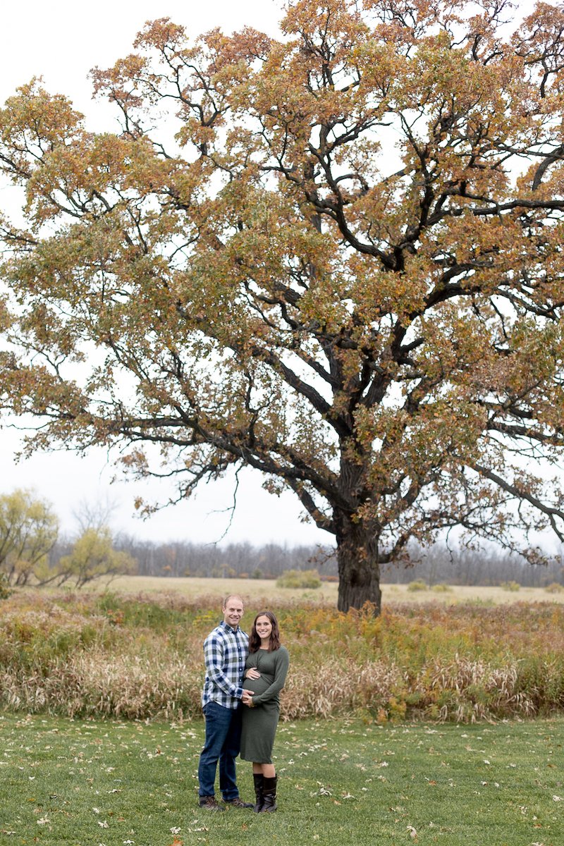 couple smiling during a Fall Maternity Session at Fox Brook Park in Brookfield with Grace Creatives photography