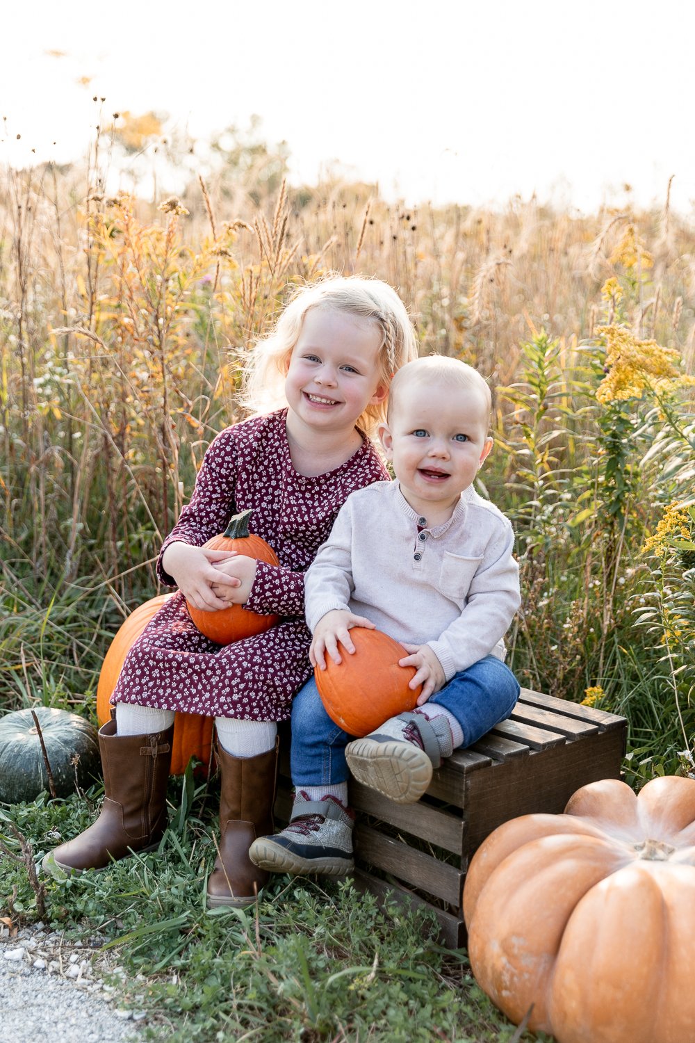 two young children holding fall pumpkins in hartung park during 2020 fall mini sessions with grace creatives