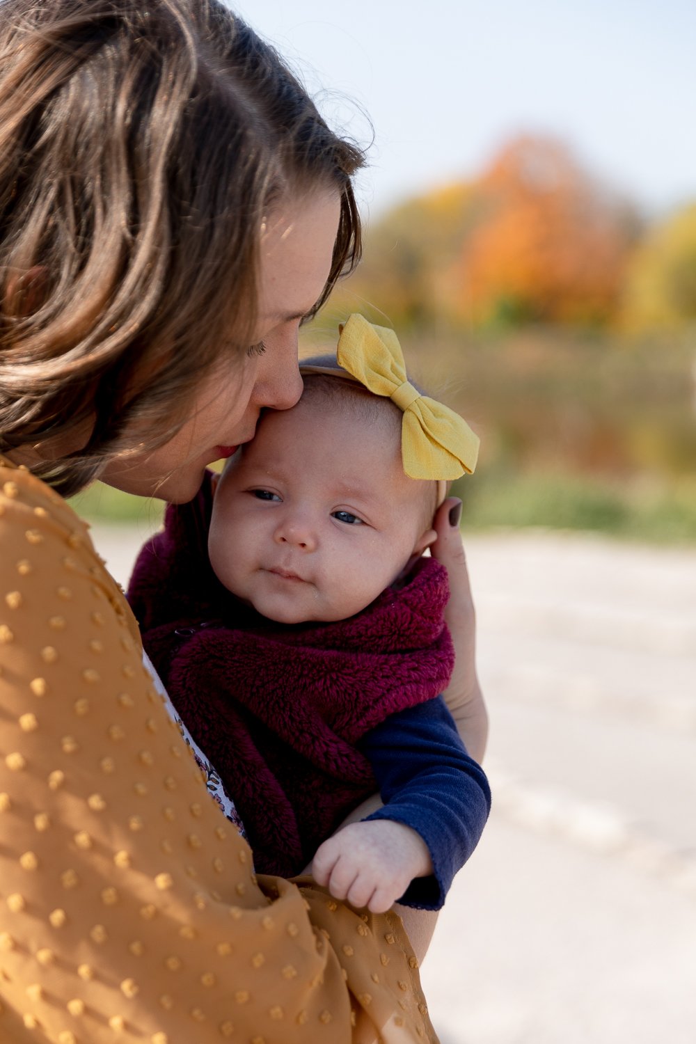 mother kissing newborn daughter during Milwaukee fall minis with grace creatives photography