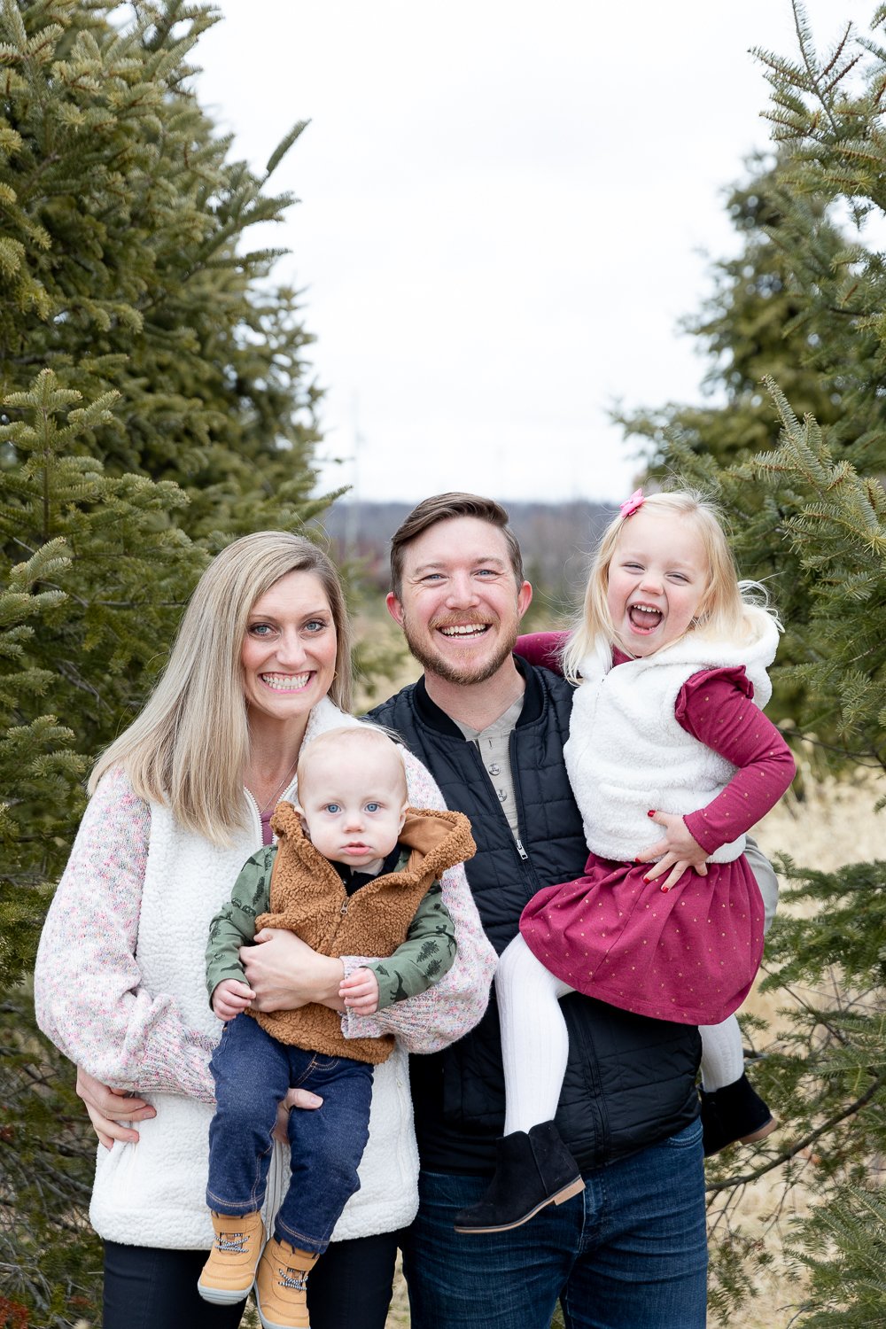 family of four smiling during family picture at Grace Creatives tree farm minis